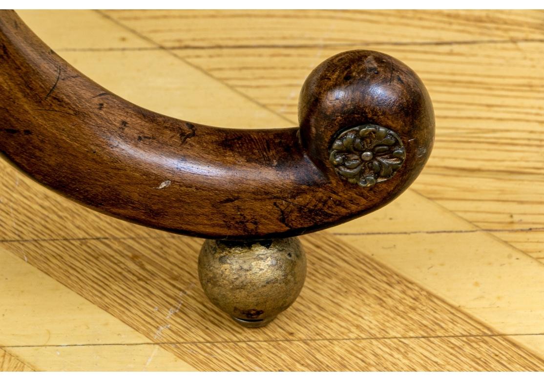 The rectangular tops are mounted on separately made wide carved bow shaped frames ending in scrolled feet. Brass rosettes are attached to the scrolled feet that are raised on gilt wood ball feet. Finely made ring turned stretchers are on the sides