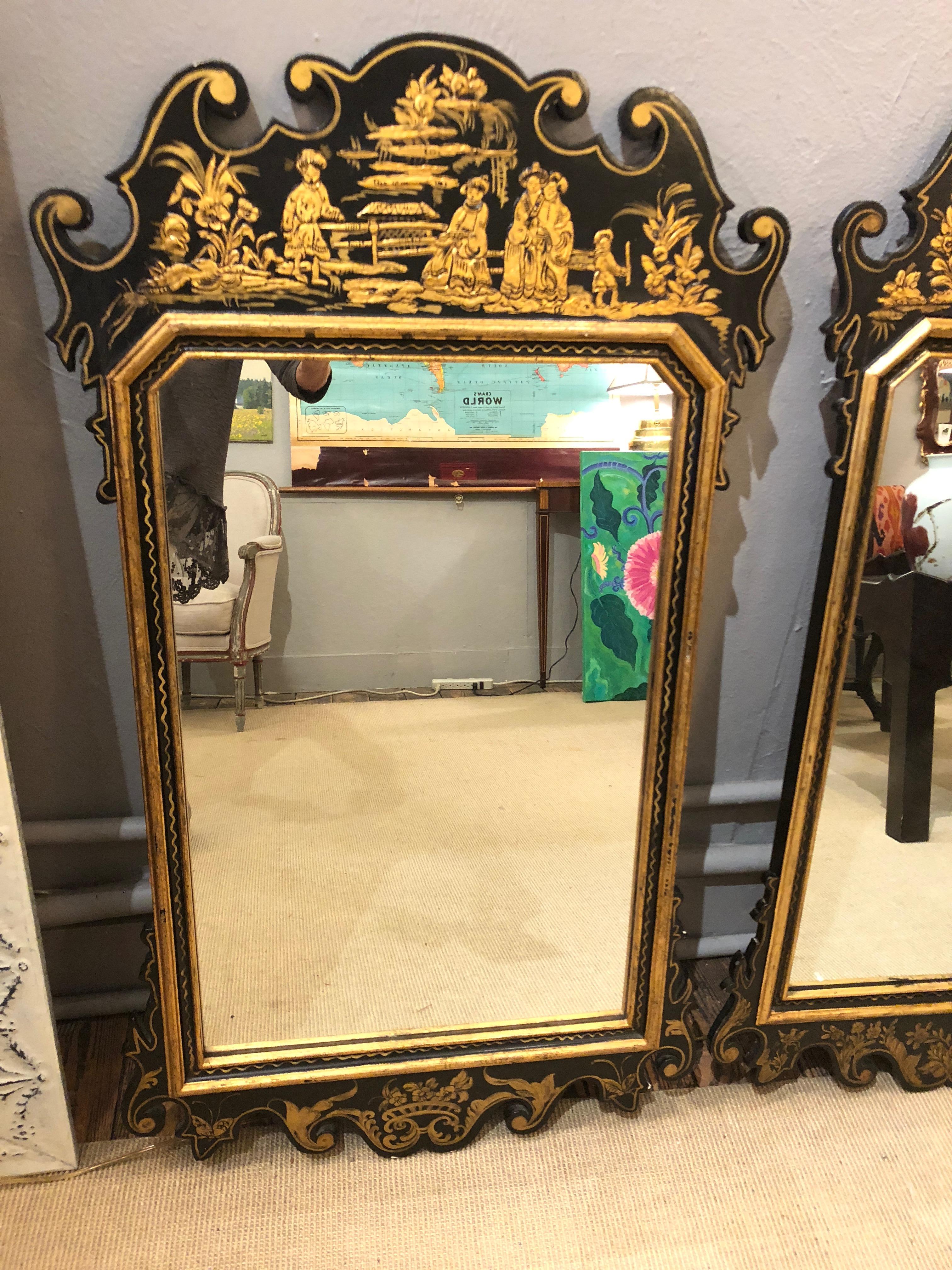 Pair of glamorous black and gold hand painted Chinoiserie style mirrors, each with unique decoration including Asian figures, pagoda, bamboo, etc.