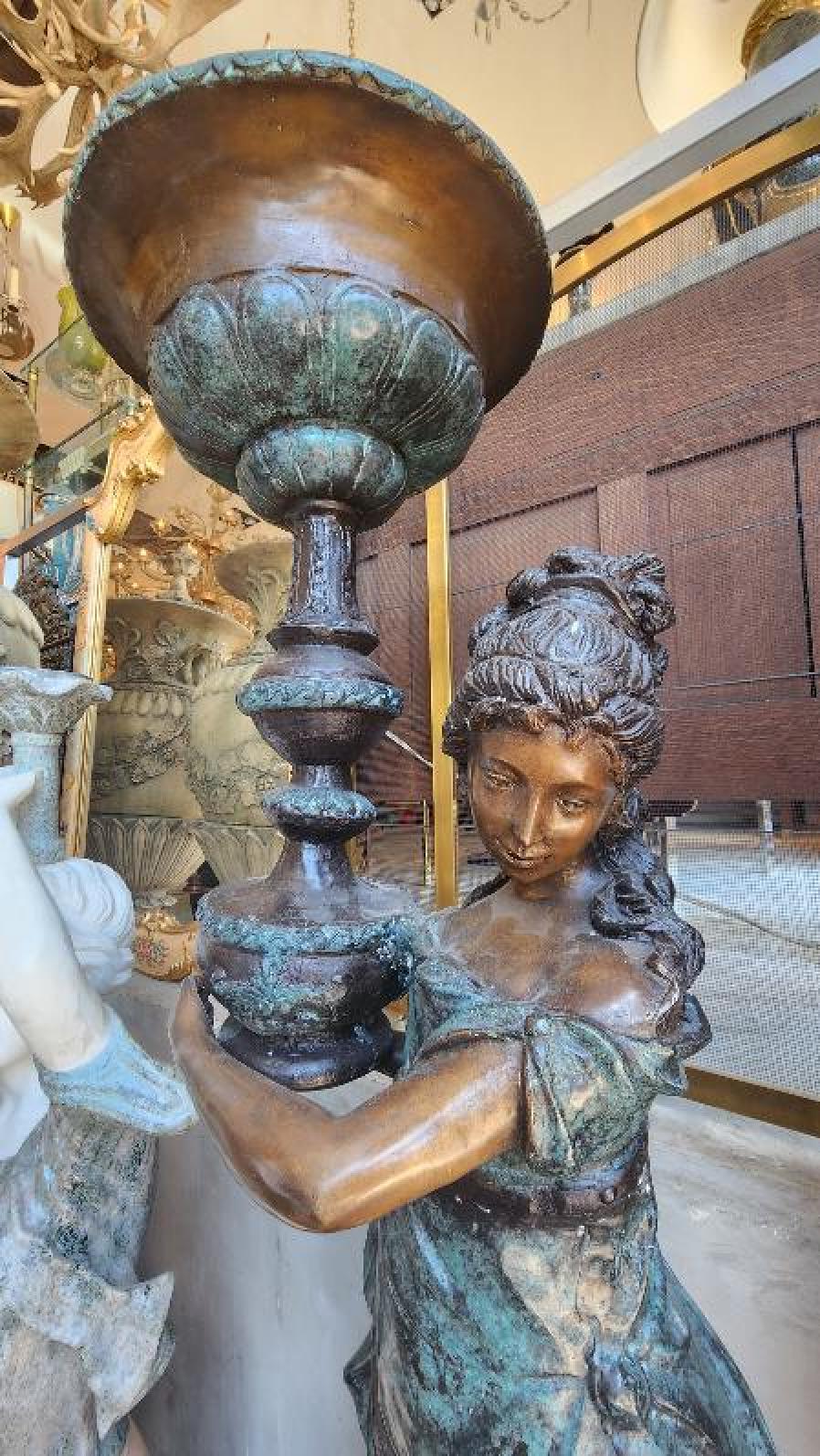 Una coppia di bellissime statue di figure femminili fuse in bronzo che tengono in mano delle lampade, che sarebbero un'ottima decorazione da esterno.