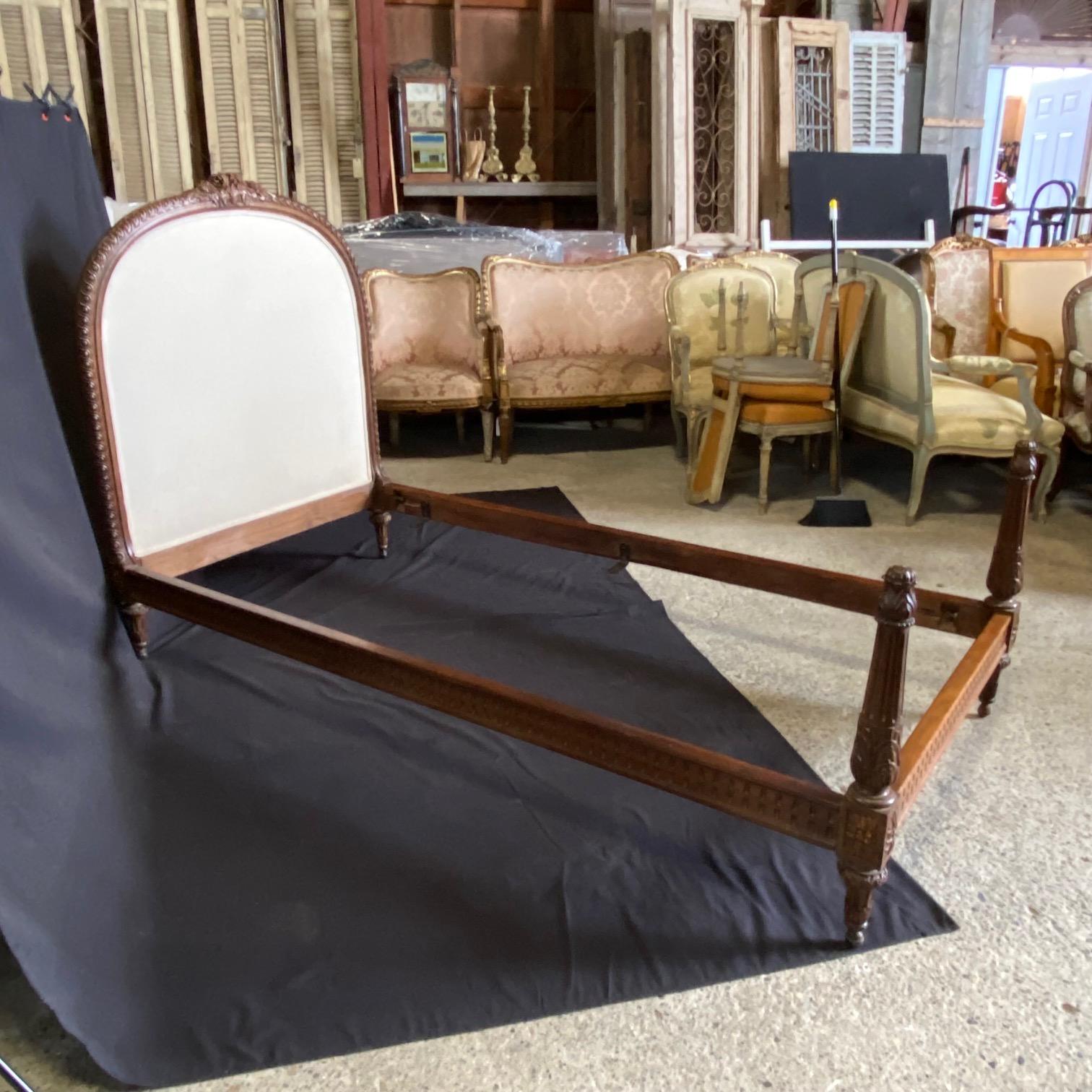 Pair of beautifully carved French Louis XVI style upholstered twin beds, circa 1930. The wood frames have carved floral and acanthus leaf decoration; please scroll through photos for the exquisite detail!  Fits standard twin mattresses (can be