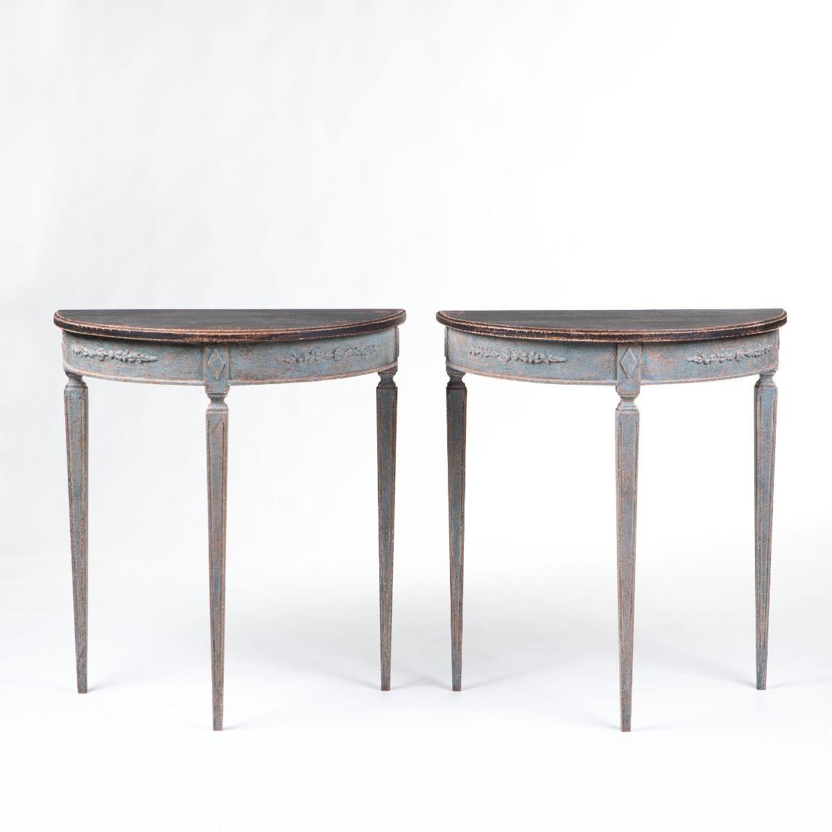 Paire de consoles Demi lune de style gustavien, fabriquées en Suède vers 1880-1900.
Les plateaux de table peints en noir présentent un bord moulé, tandis que la base est finie dans un élégant ton bleu.
La façade est décorée de guirlandes florales