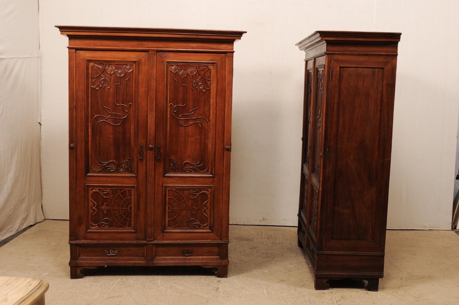 A tall pair of Swedish Art Nouveau wardrobe cabinets with beautifully carved fronts from the early 20th century. This pair of antique armoires from Sweden each feature a pair of exquisitely carved two paneled doors, framed within vertically fluted