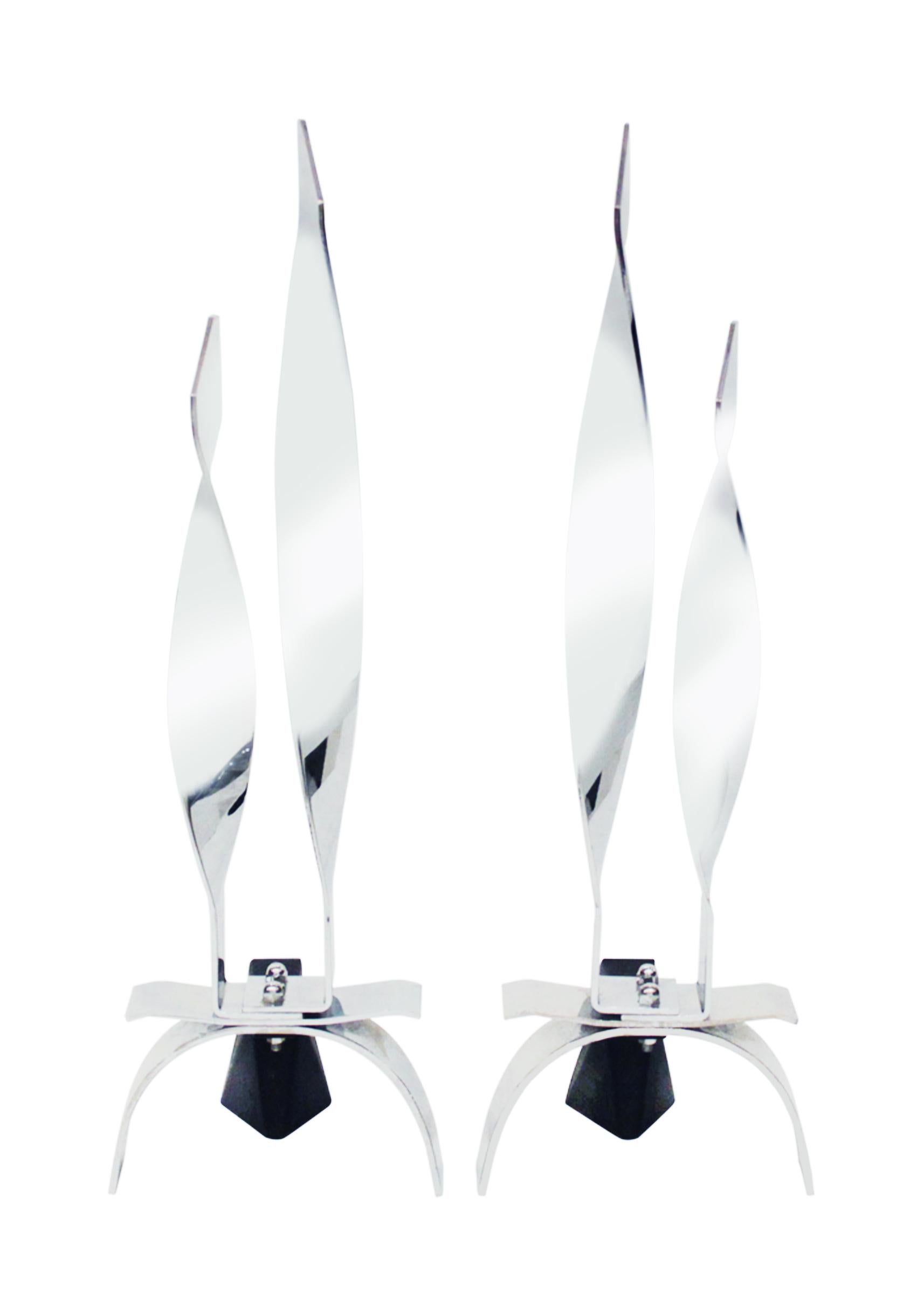 Pair of flame andirons in polished chrome, American 1960's.  These andirons are very chic. The flames of a fire would reflect beautifully off the gently curving surfaces of the andirons.  Dimensions are for each.