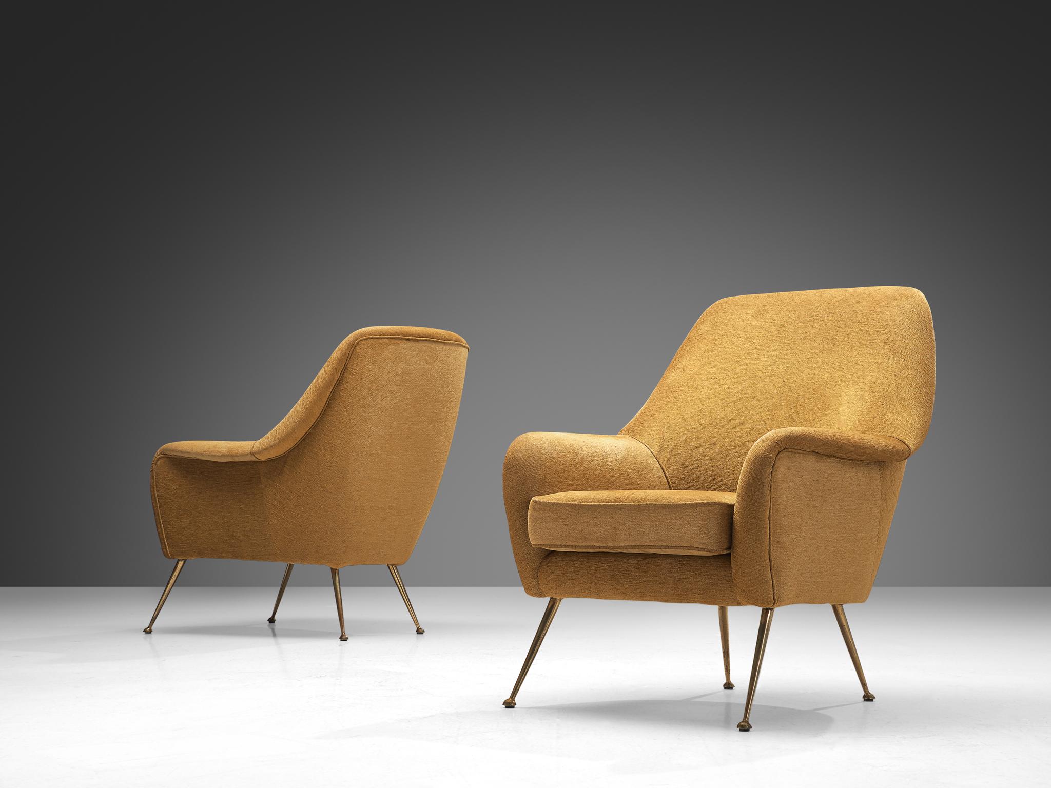 Pair of lounge chairs, fabric, brass, Italy, 1950s.

This Italian armchair is characterized by an elegant aesthetic due to its curvaceous lines and round edges. The seating area is supported by sleek outward-facing legs in brass. The back elegantly