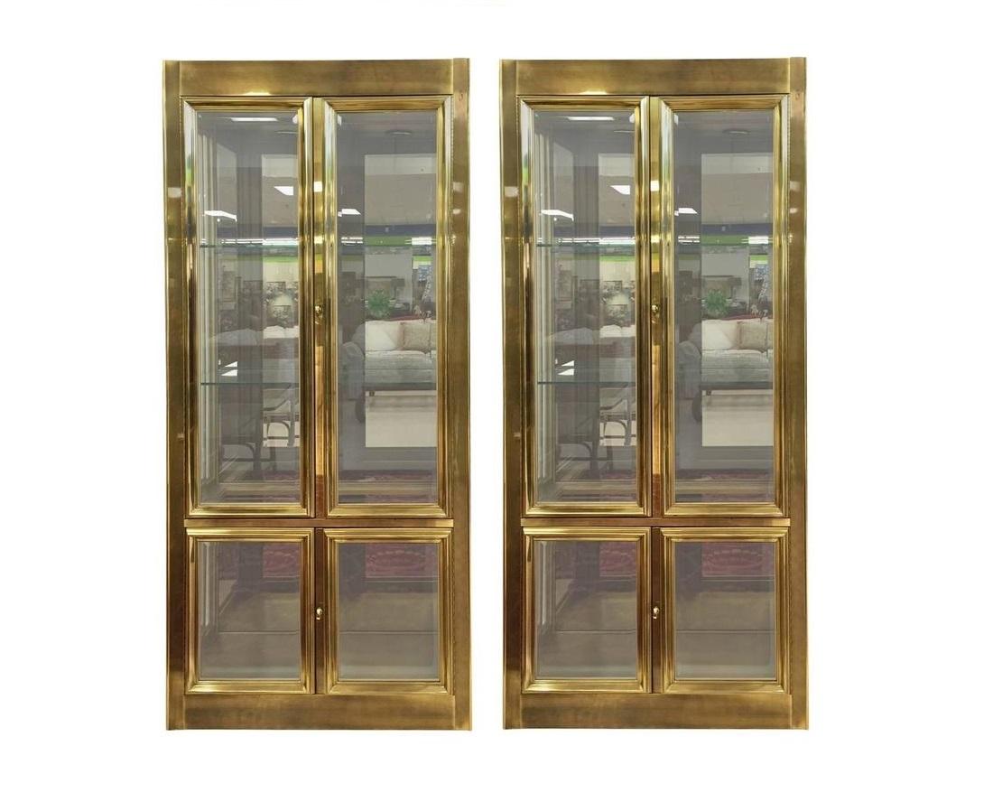 Pair of aged brass vitrines of impeccable quality from Mastercraft, circa 1970s. Elegant brass-clad vitrine has four heavy doors (two large on top, two small on the bottom) that open to reveal thick adjustable glass shelves with a plate ridge for