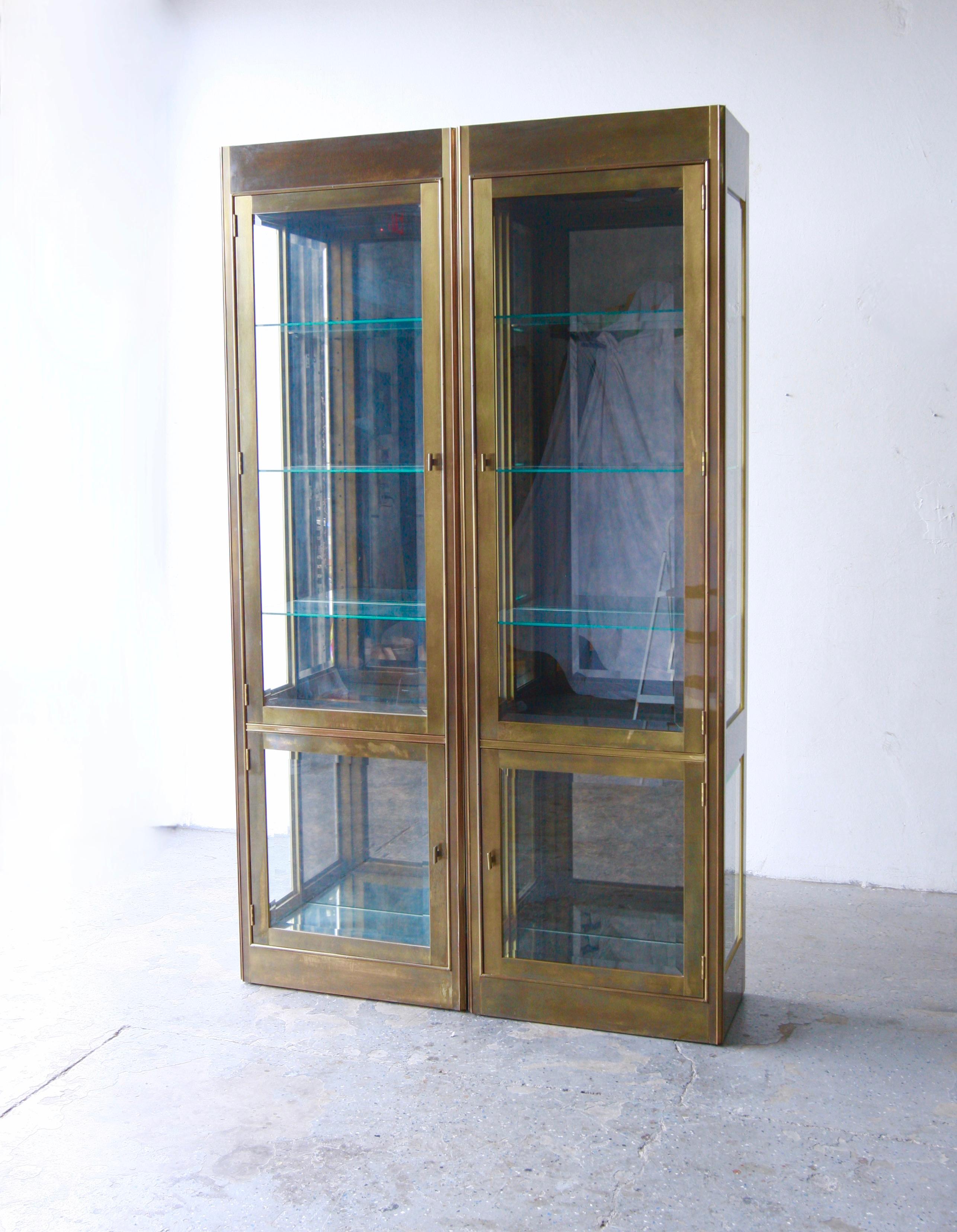
Pair of aged Patina brass vitrines of impeccable quality from Mastercraft, circa 70s /80’s . Each Elegant brass-clad vitrine  opens to reveal  adjustable glass shelves with a plate ridge for displaying plates or other flat items. The glass cabinet