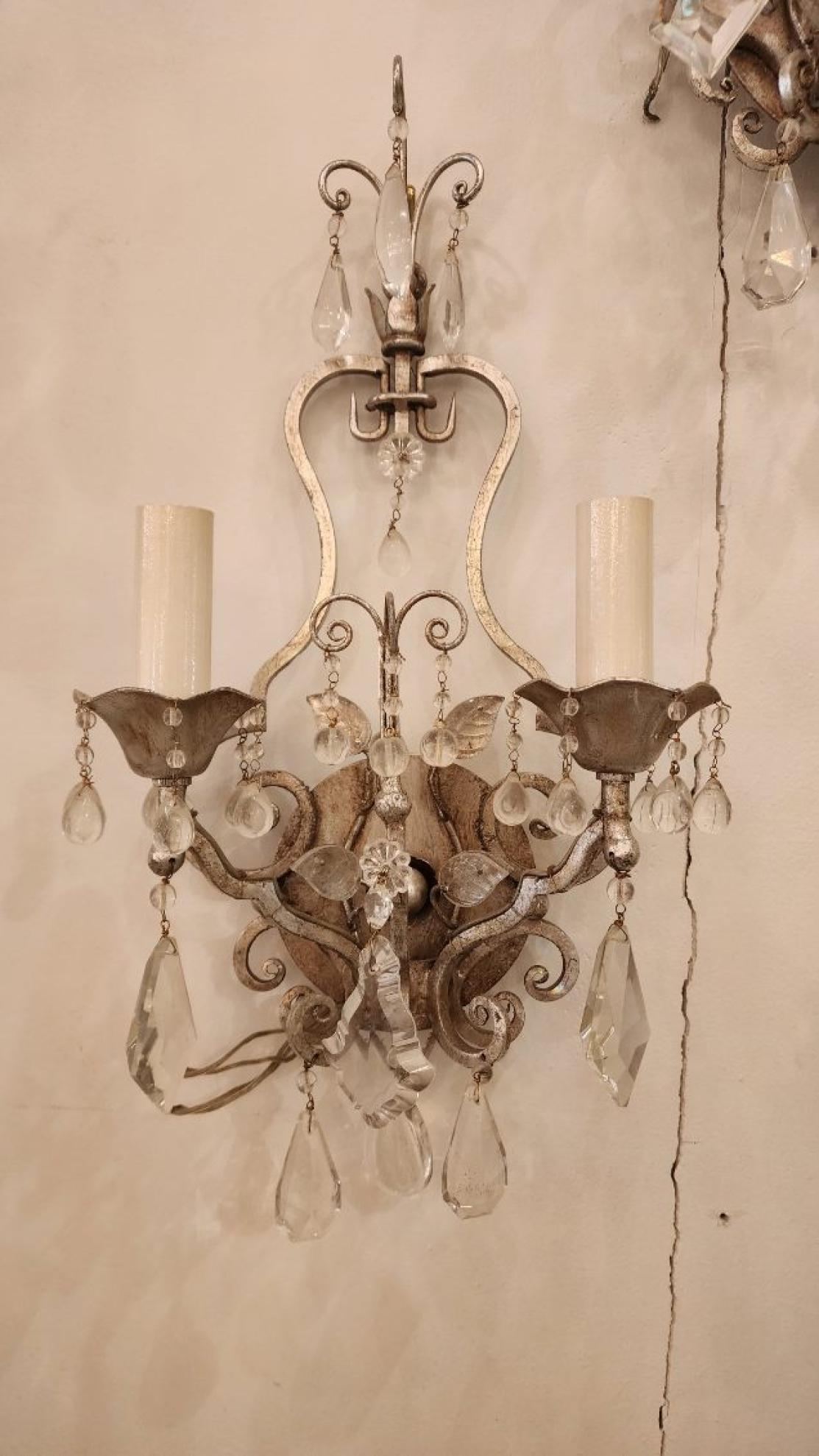 Cette annonce présente une paire d'élégantes appliques en métal et en verre, chacune avec deux lumières. Le style de ces appliques s'inspire d'un designer français nommé Maison Bagues, dont le style fusionnait sans effort l'élégance française