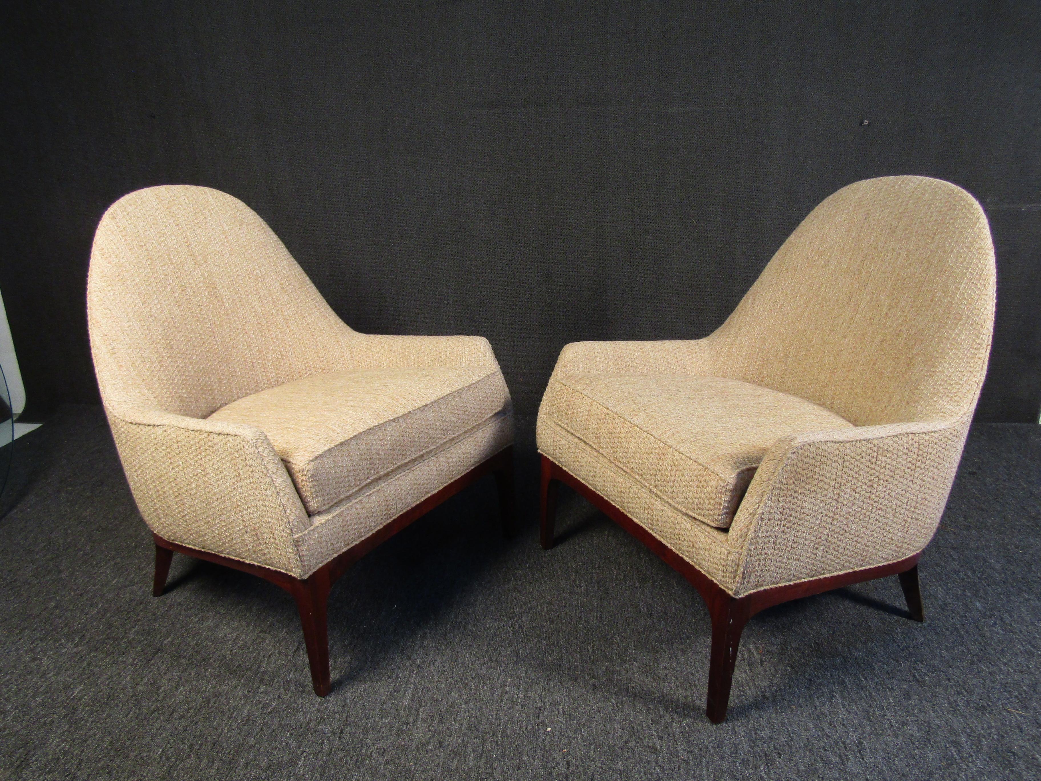 Combining a warm beige upholstery with rich walnut legs, this pair of Mid-Century Modern lounge chairs is perfect for any reading room or home library. Please confirm item location with seller (NY/NJ).