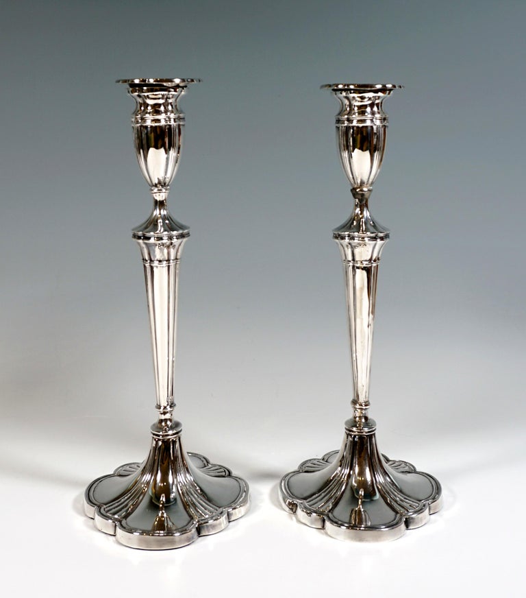 Pair of silver candle holders on a sweeping, oval-cloud-shaped base, framed and profiled segments pulled up in the middle and converging to form a grooved ring, widening, profiled shaft corresponding to the plan, attached vase-shaped spouts with