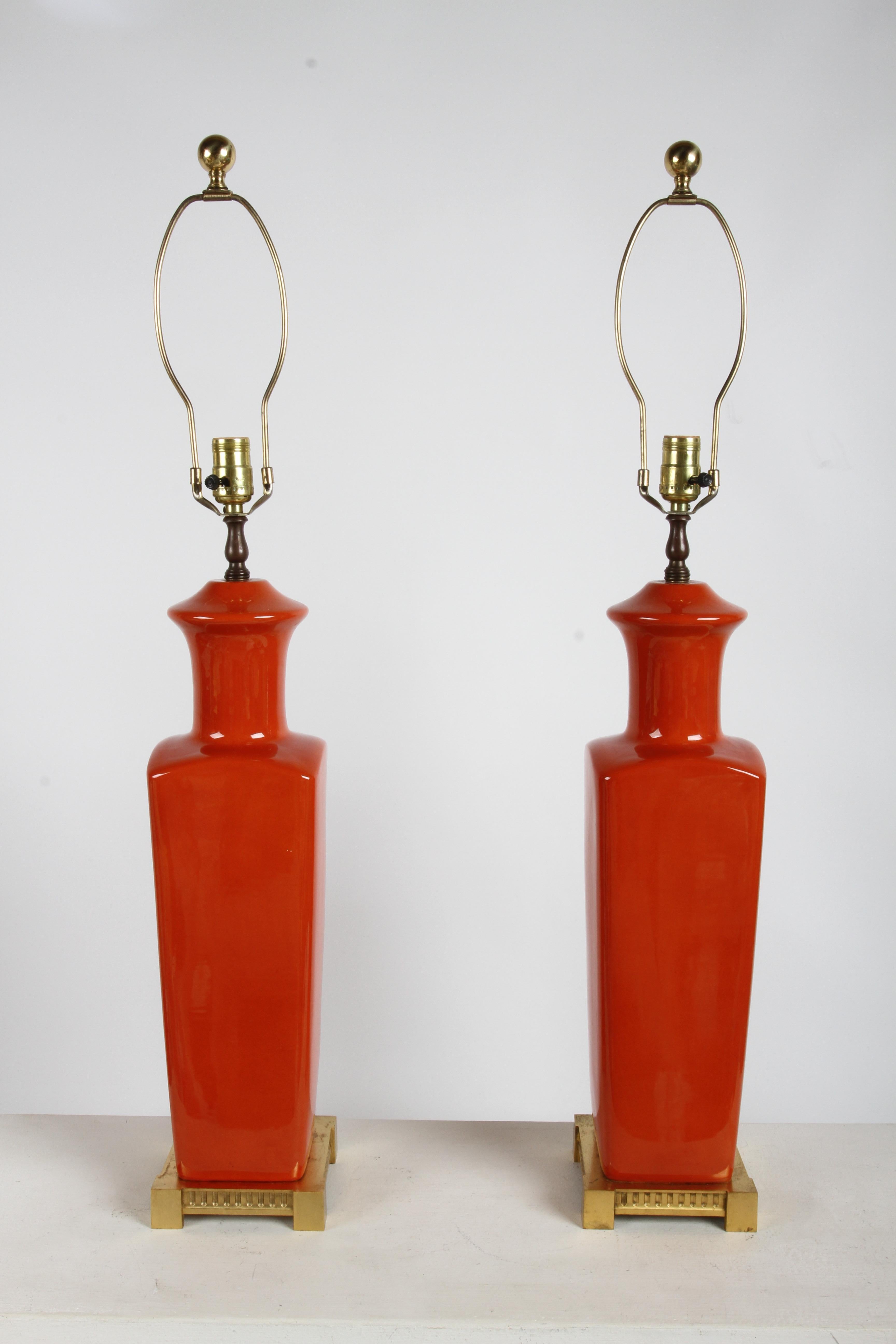 Stunning pair of vintage modern tall slender ceramic urn table lamps, in a deep orange glaze with gold plated square bases. Made in France stamped to underside of base, with some wear to one to bases. Height is to top of harp.   