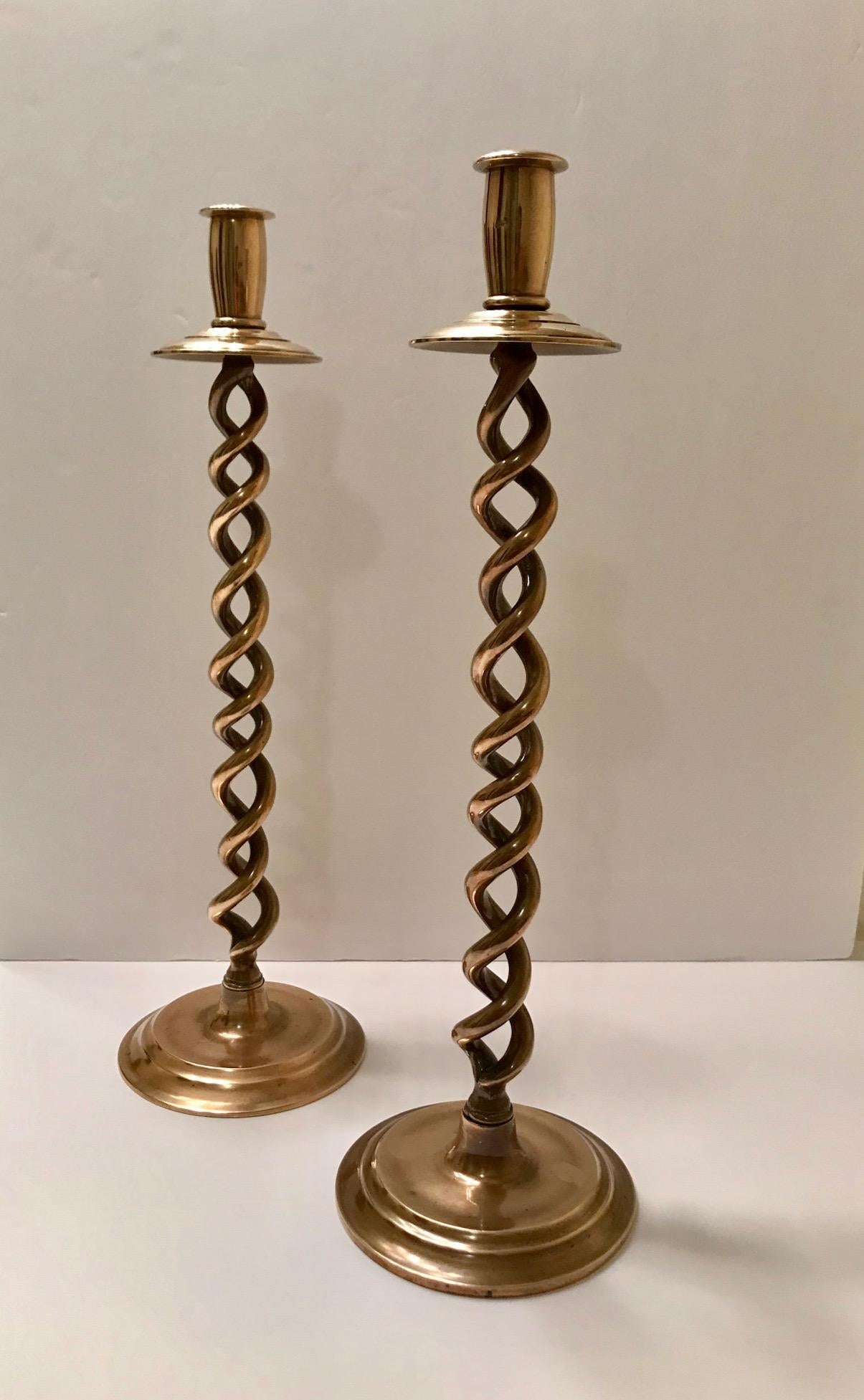 Pair of Mid-Century Modern candlesticks with Victorian Revival design. Beautiful candleholders in cast polished brass with braided stems or barley twist design. The candle holders have circular stepped bases and have solid weight to the touch. Minor