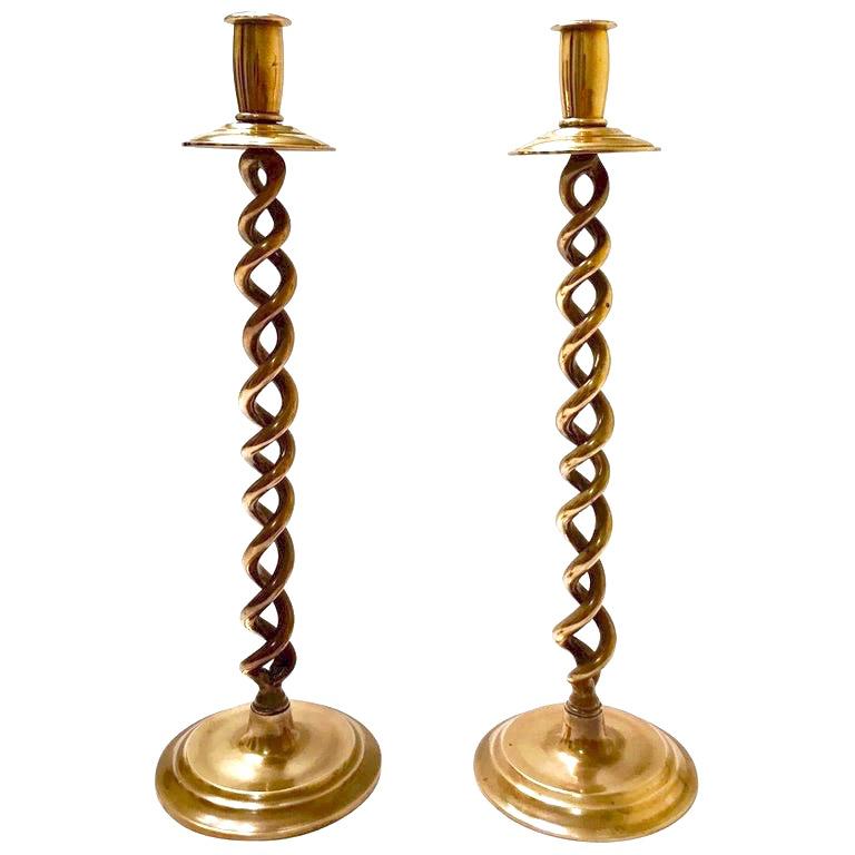 Pair of Mid-Century Modern candlesticks with Victorian Revival design. Beautiful candleholders in cast polished brass with braided stems or barley twist design. The candle holders have circular stepped bases and have solid weight to the touch. Minor