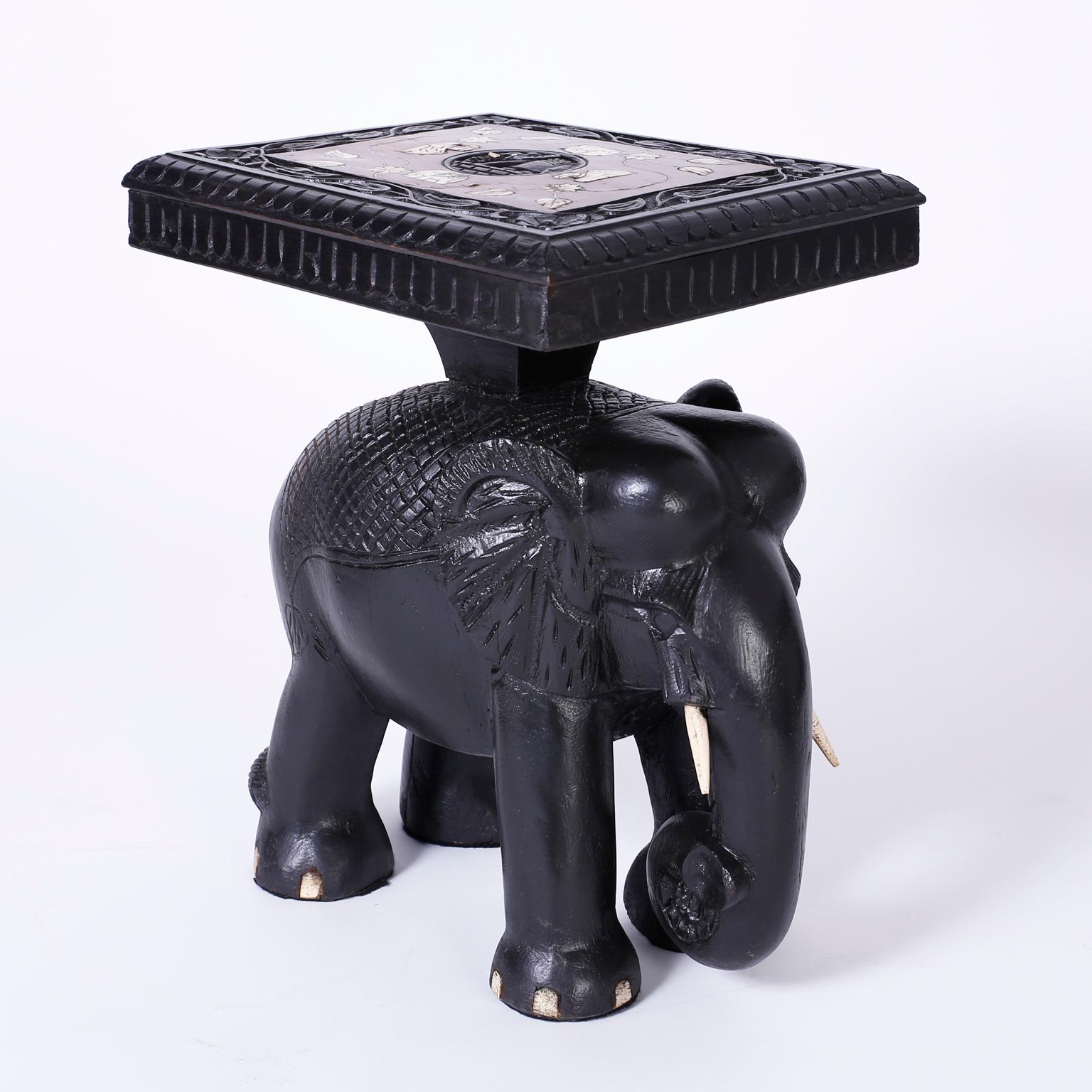 Exotic pair of end tables or stands each with floral bone inlays on rosewood tops and ebonized hand carved borders on carved wood elephant bases with bone tusks. A matching coffee table is also available, as seen in the last photo of the listing.
