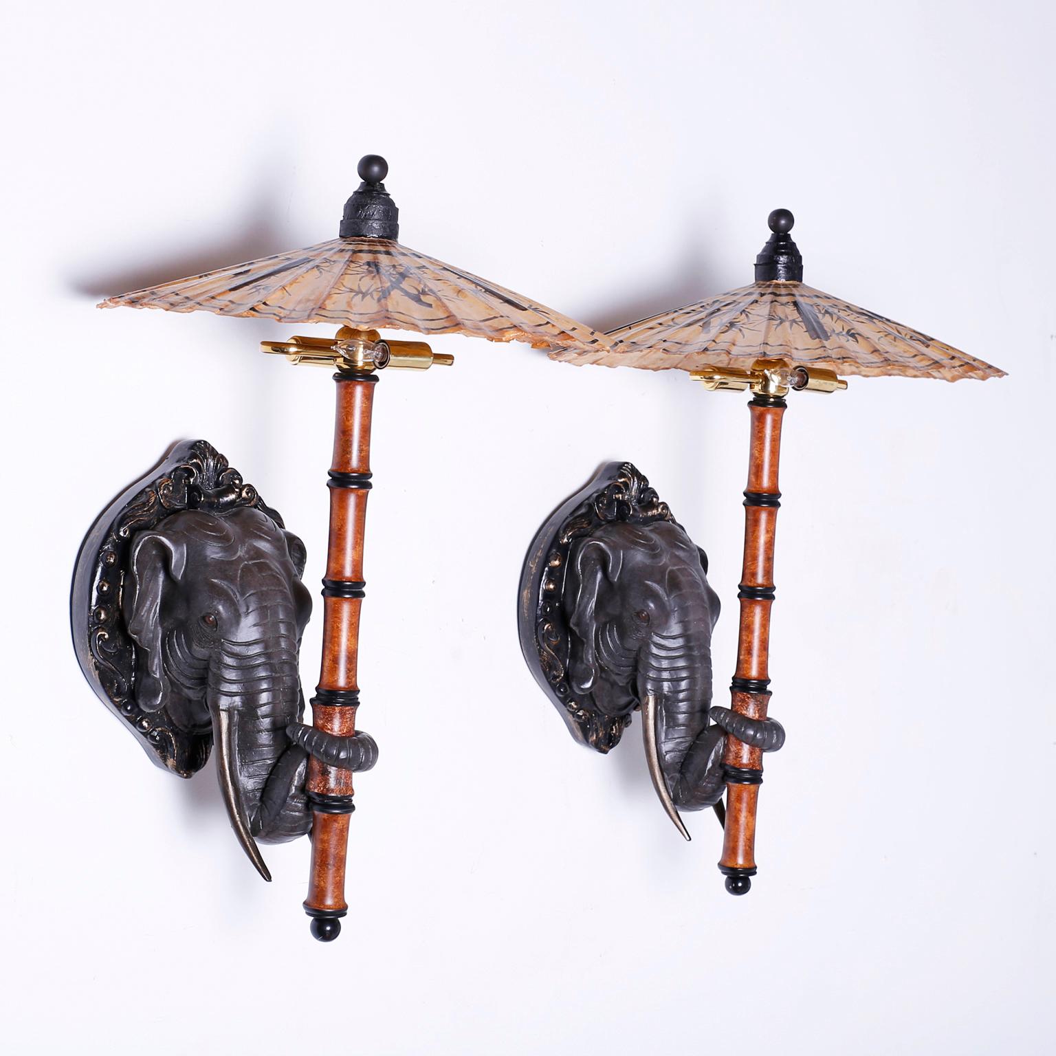 Enchanting pair of electrified wall sconces crafted in composition, depicting an elephant holding a bamboo and lacquered paper umbrella with his trunk.