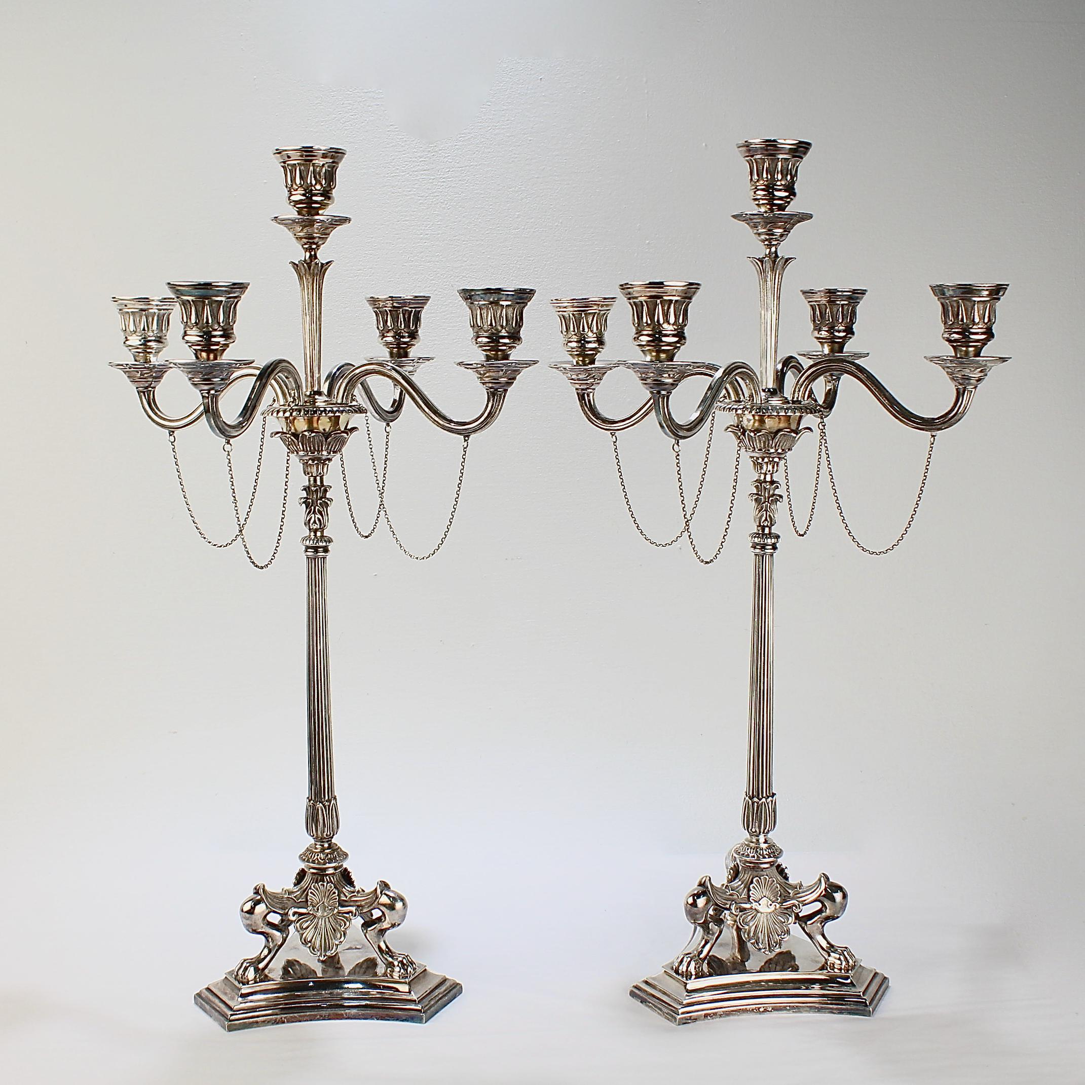 A rare pair of Victorian Neoclassical Revival silver plated candelabra by Elkington & Co.

Each candelabrum has a fluted column that rests on three paw feet that also support anthemion aprons. The feet are bolted to a stepped base.  

The central
