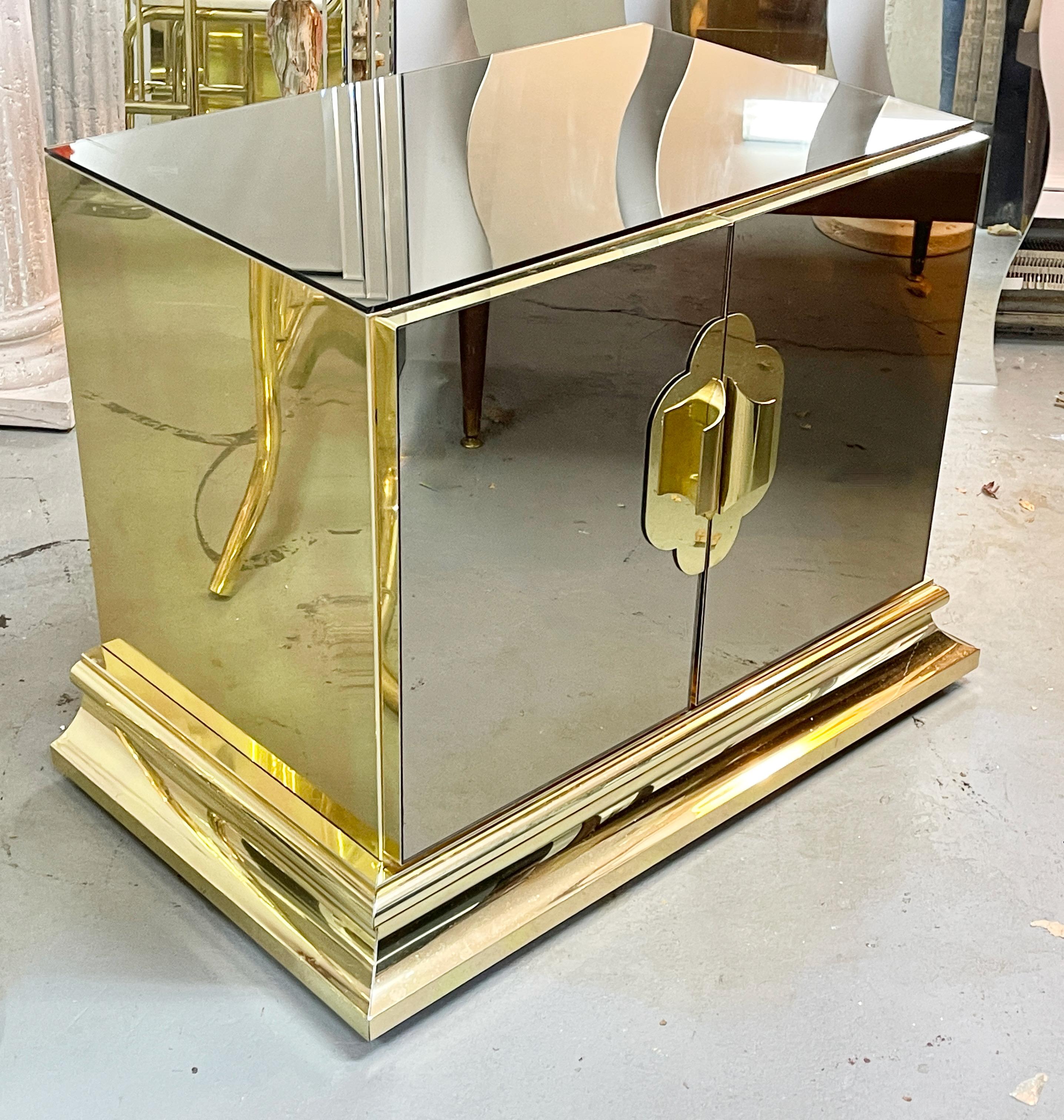 Pair of 1980s bedside cabinets manufactured by Ello Furniture Manufacturing Co. and designed by O. B. Solie as part of Ello's Regency Imperial collection. 
Double door cabinets are clad in bronzed mirrored glass with gilt brass escutcheons and