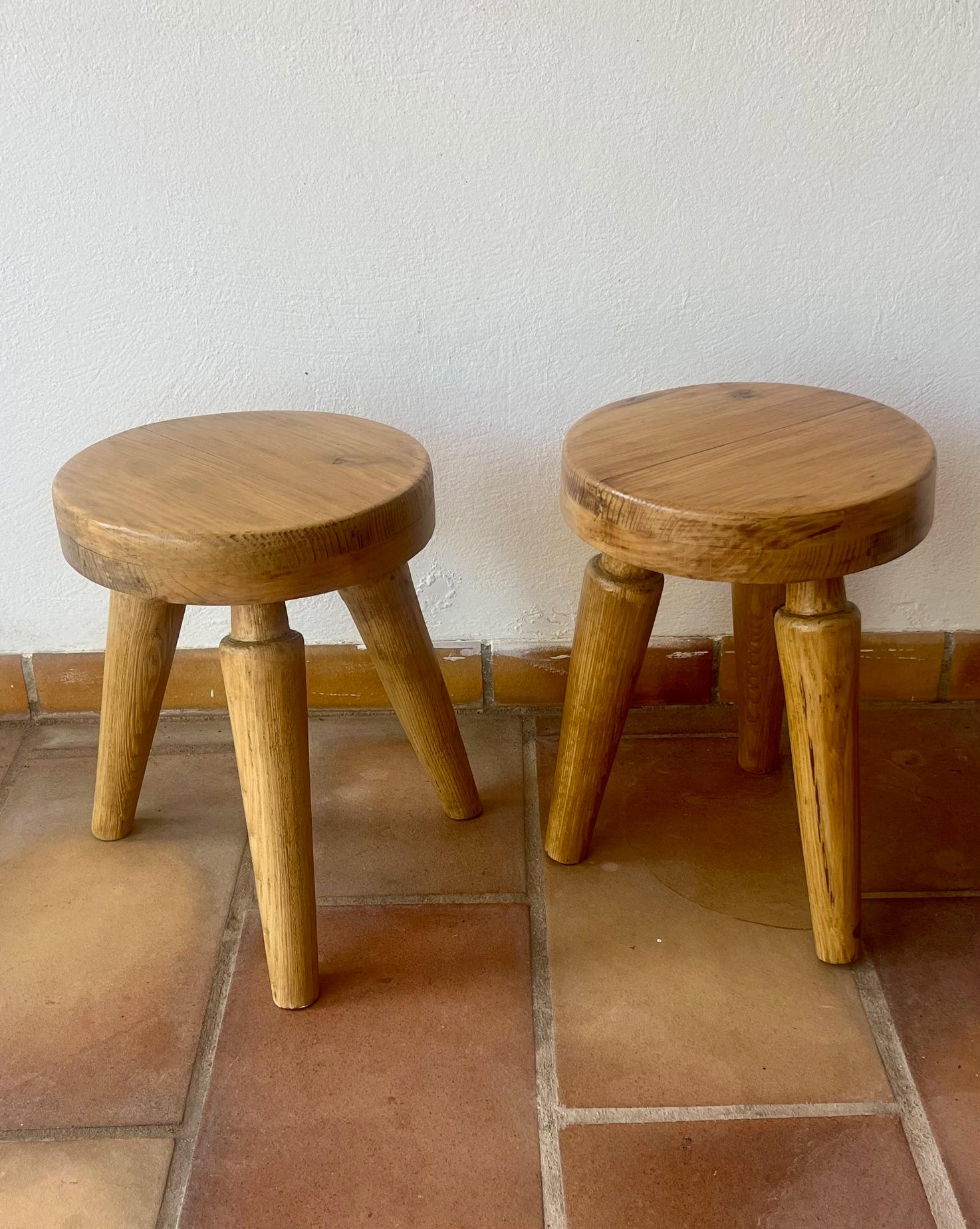 A Pair of three legged stools.
The thick round seating made in elm wood.
The 3 tapered legs made in pine wood 
