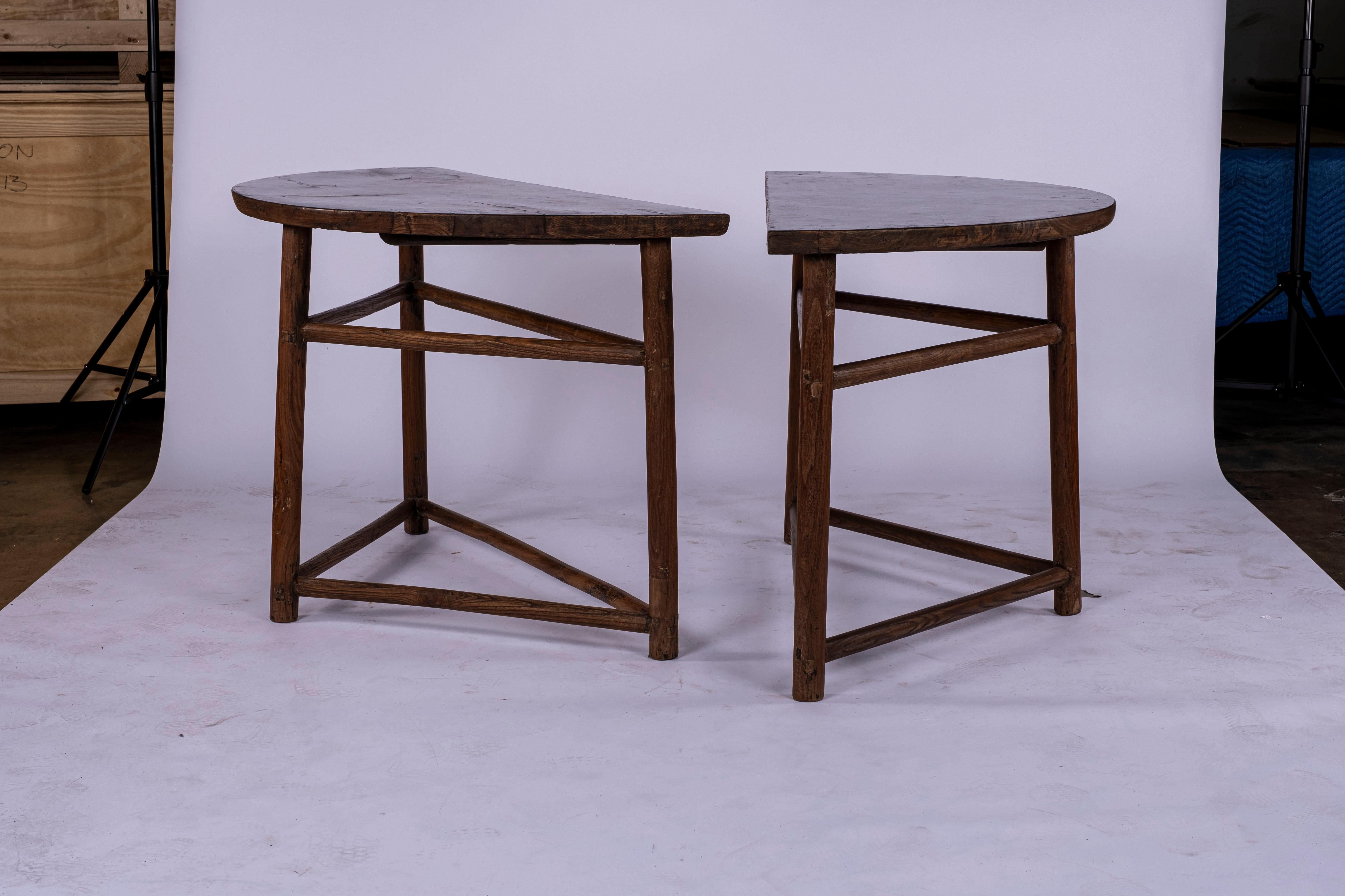 Pair of architectural elm wood demi lune consoles with lacquered black tops. Tops have worn appearance consistent with age and use. Difficult to photograph because of black lacquer. If you are looking for pristine flat tops do not purchase these.