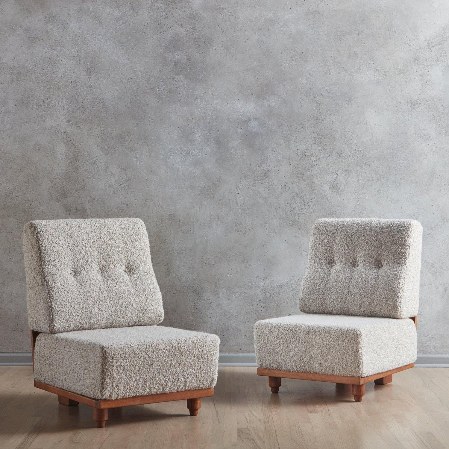 A pair of ‘Elmyre’ lounge chairs by Guillerme et Chambron. These chairs have sculptural oak frames with cutout details and sit low to the ground. They have thick removable cushions newly reupholstered in a beautiful Teddy Alpaca fabric with tuft