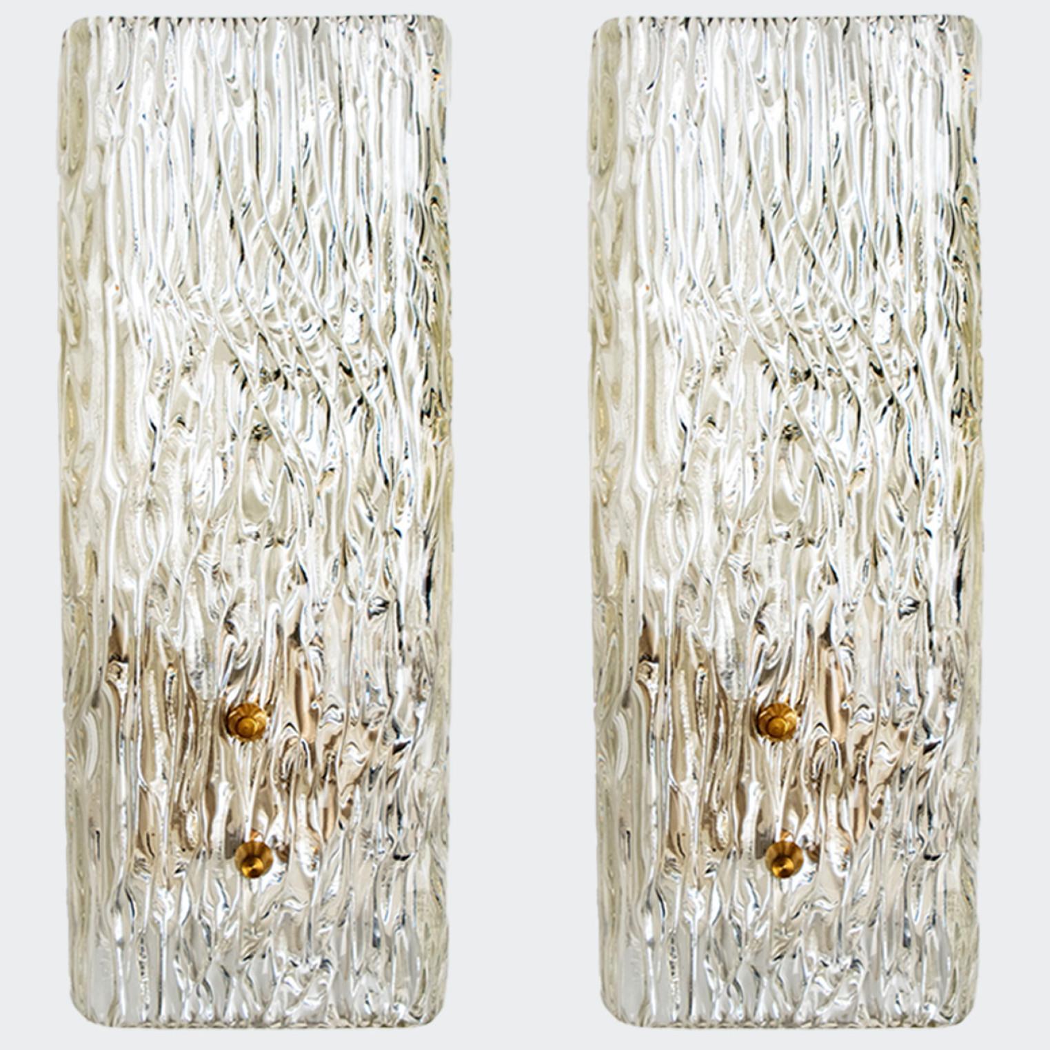 Beautiful and elegant modern brass wall lights or sconces, manufactured by J.T. Kalmar Austria in the 1960s. Lovely design, executed to a very high standard.

Each light has one solid textured glass column on it. Clean lines to complement all