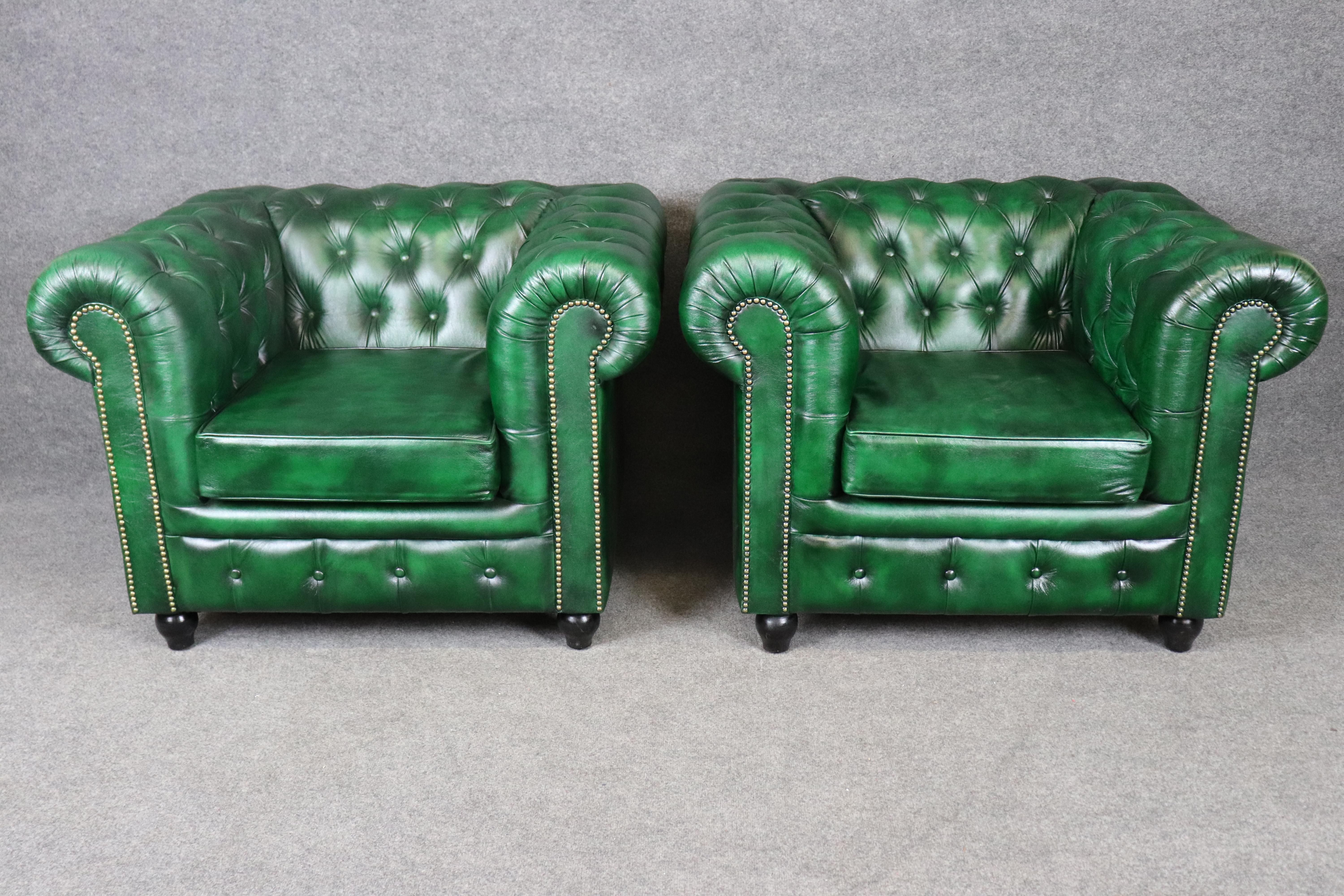 Questa straordinaria coppia di sedie club Chesterfield inglesi, che misurano 41,5 pollici di larghezza, incarna una raffinatezza senza tempo con un tocco audace. Rivestita in ricca pelle verde smeraldo, ogni sedia presenta la classica imbottitura