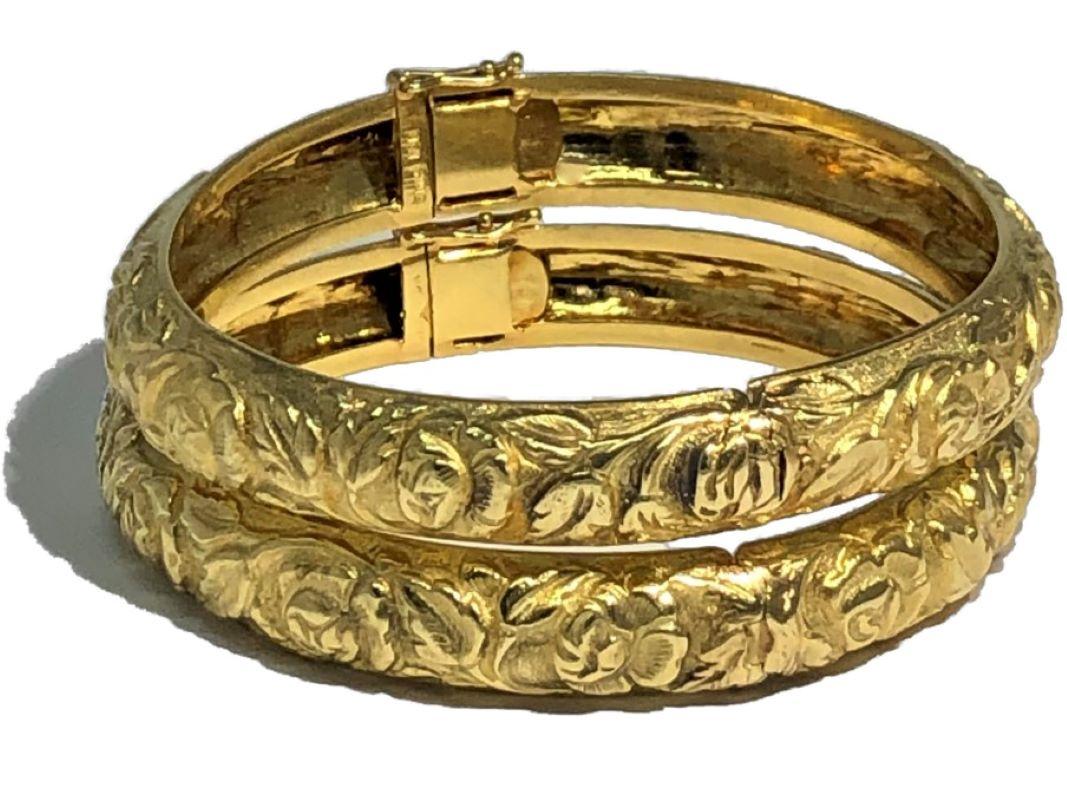 This charming pair of 18K Yellow Gold bangles by designer Emis Beros, are adorned over their entire bombee surface with an intricate, repeating floral motif pattern. Fashioned in very high relief, the flowers are accented by bright polished