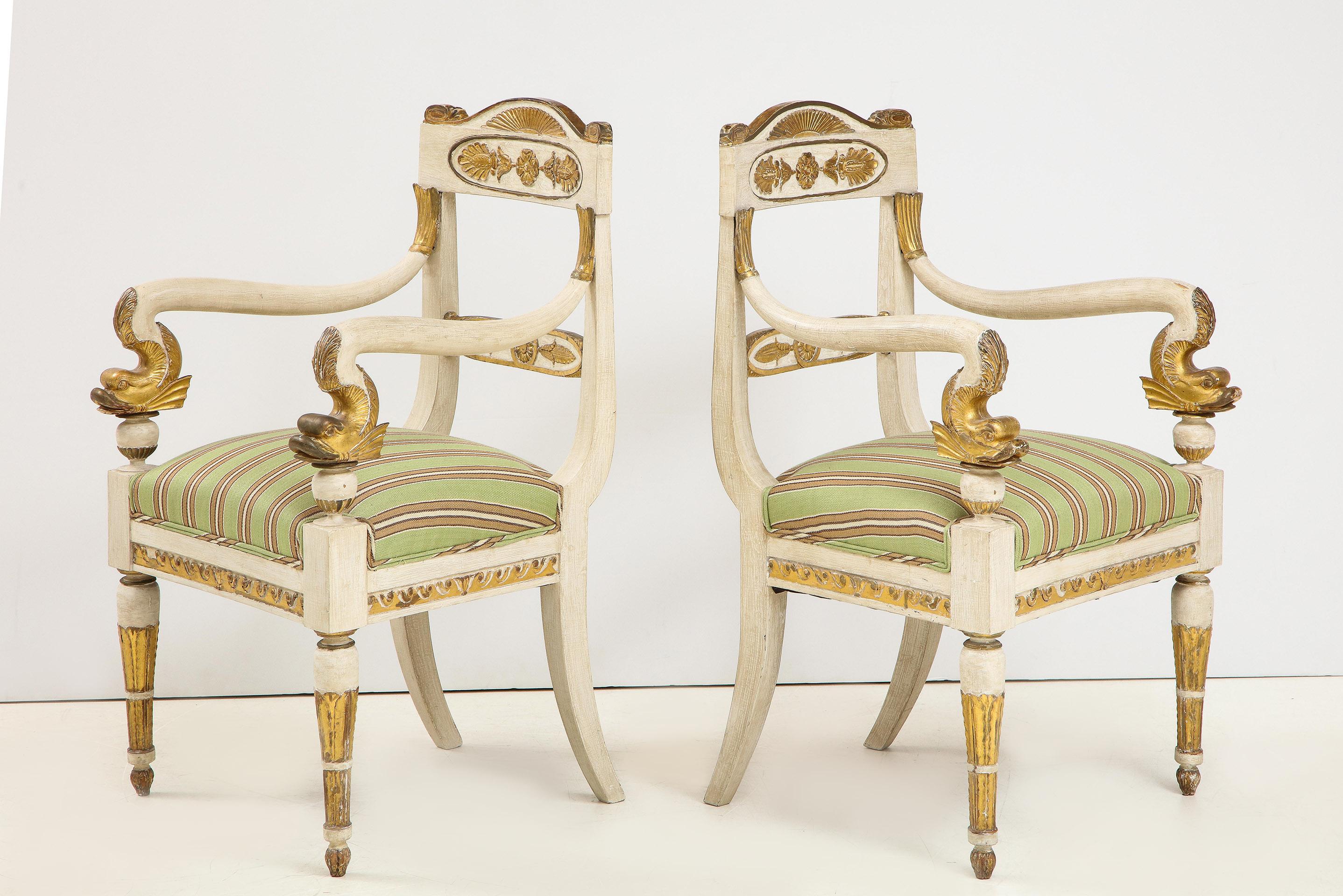 Pair of Italian Empire white painted and gilt arm chairs with carved gilt dolphin arms.