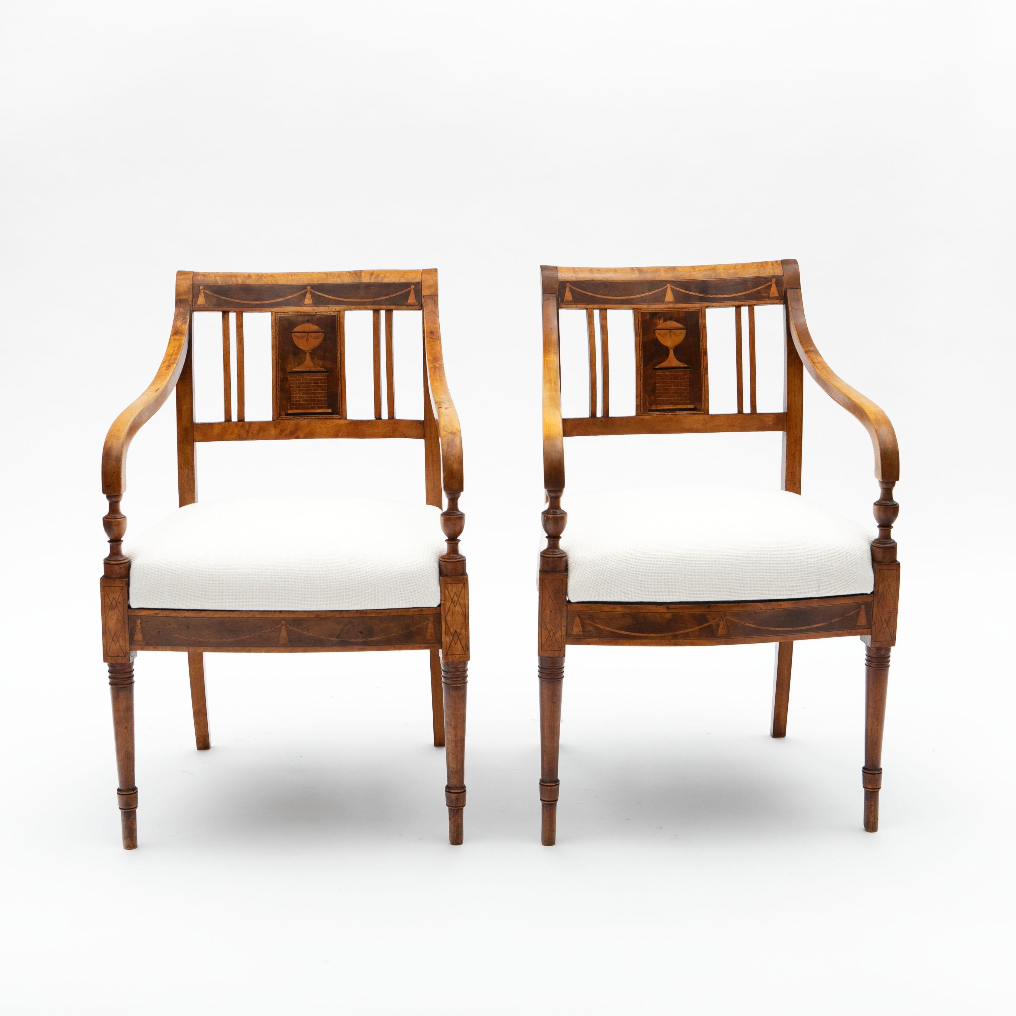 Paire d'élégants fauteuils Empire à la patine magnifiquement préservée.

Cette paire de fauteuils Empire est fabriquée en bouleau massif et présente des incrustations rectangulaires en acajou plus foncé sur les dossiers et les tabliers.
Les chaises
