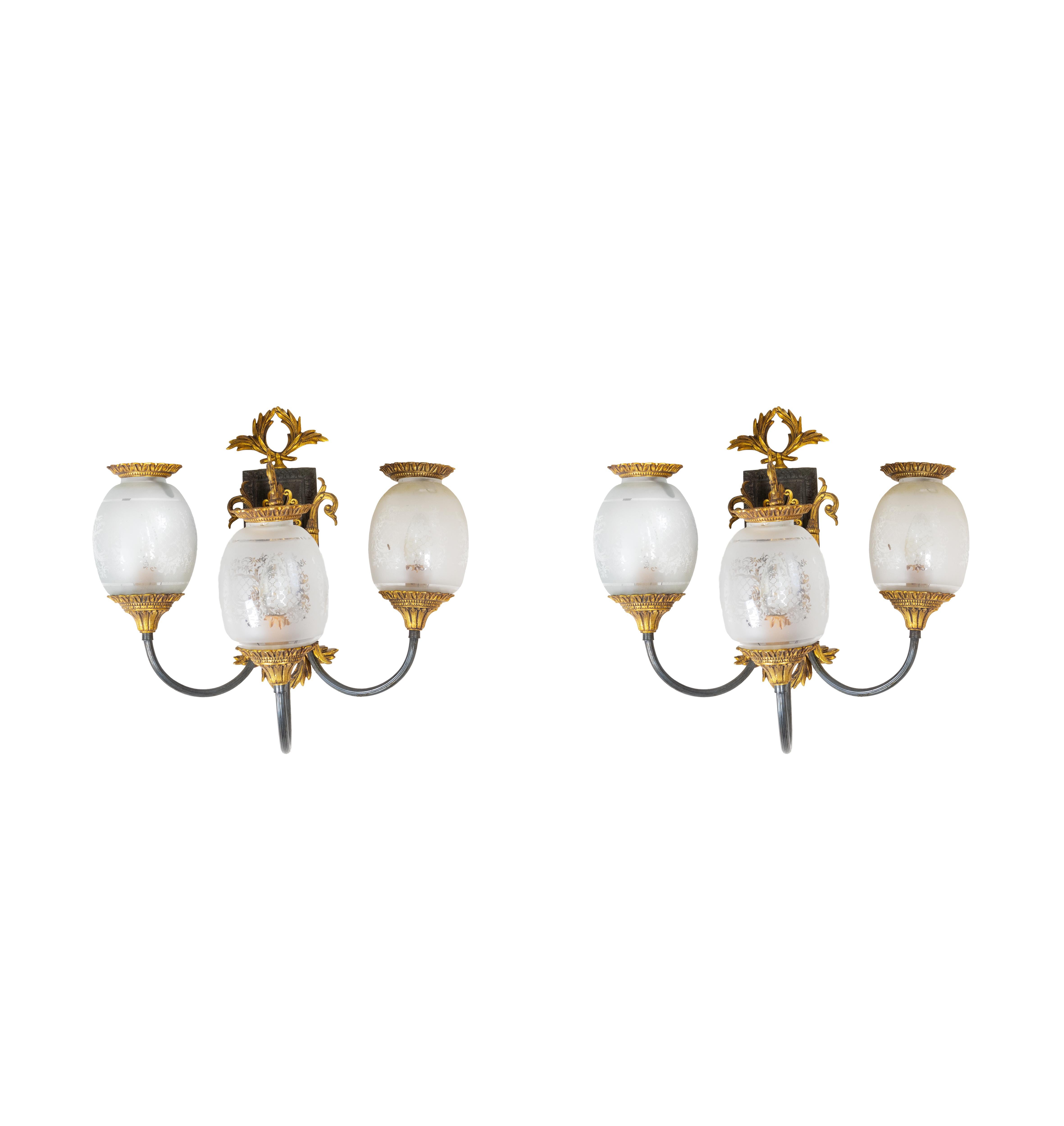 Elégante paire d'appliques murales en bronze d'inspiration Empire avec trois lumières de style lampe à huile, mêlant la grandeur néoclassique inspirée par l'innovation décorative du mouvement Wiener Werkstätte.

Fabriquée au 20e siècle, cette paire