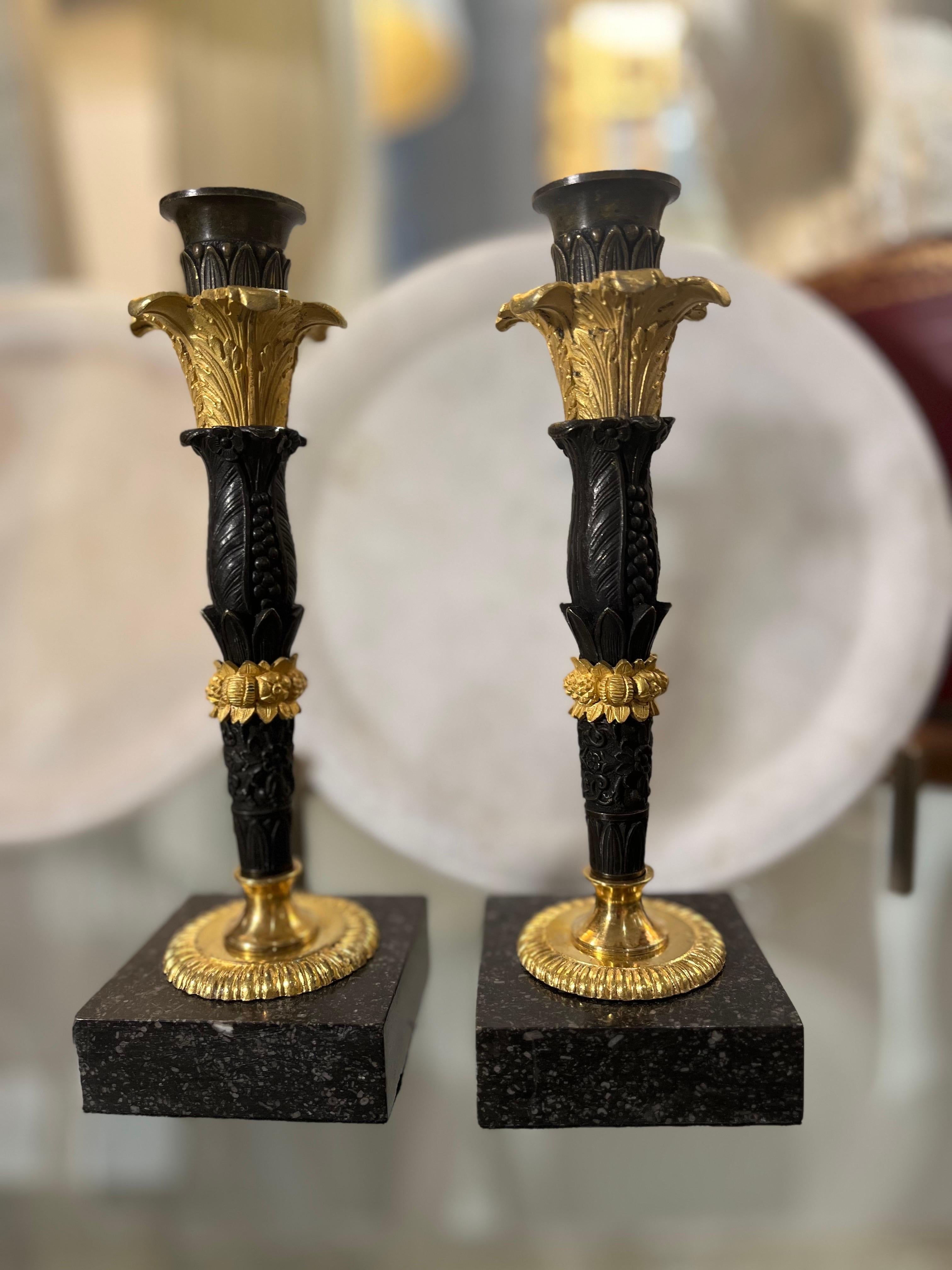 Pareja de candelabros Imperio de bronce bruñido y bronce dorado, ormolu. La base es de mármol cuadrado, sobre la que descansa una base circular dorada que sostiene la columna.