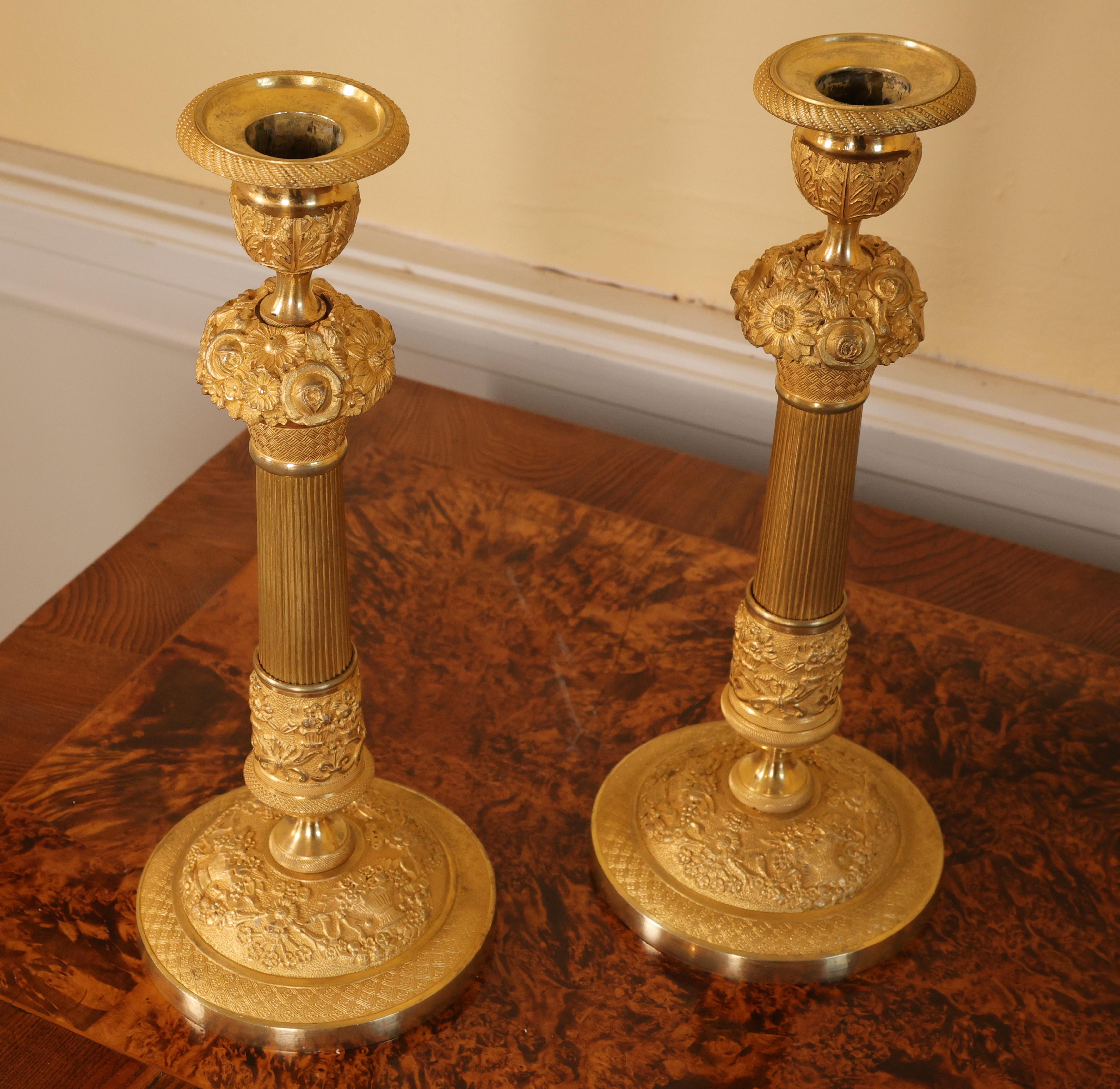 Coppia di candelabri Impero francesi con collari luminosi abbinati, riccamente decorati in bronzo dorato brunito. La sezione centrale è elegantemente scanalata e presenta una ghirlanda con abbondanti decorazioni floreali. La doratura brunita dei