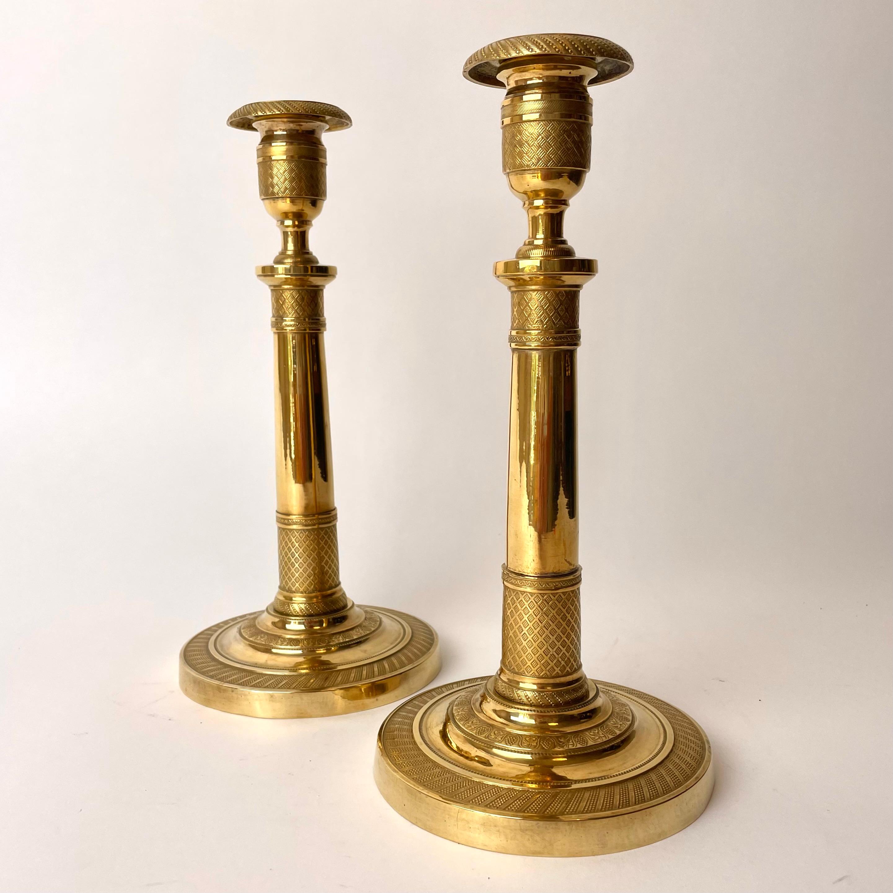 Pair of Empire Gilded Bronze Candlesticks.

Elegant and restrained, this pair of Candlesticks is treated with almost an architectural quality. Different kinds of checkered patterns in the gilded bronze give the column intricate detailing. The base