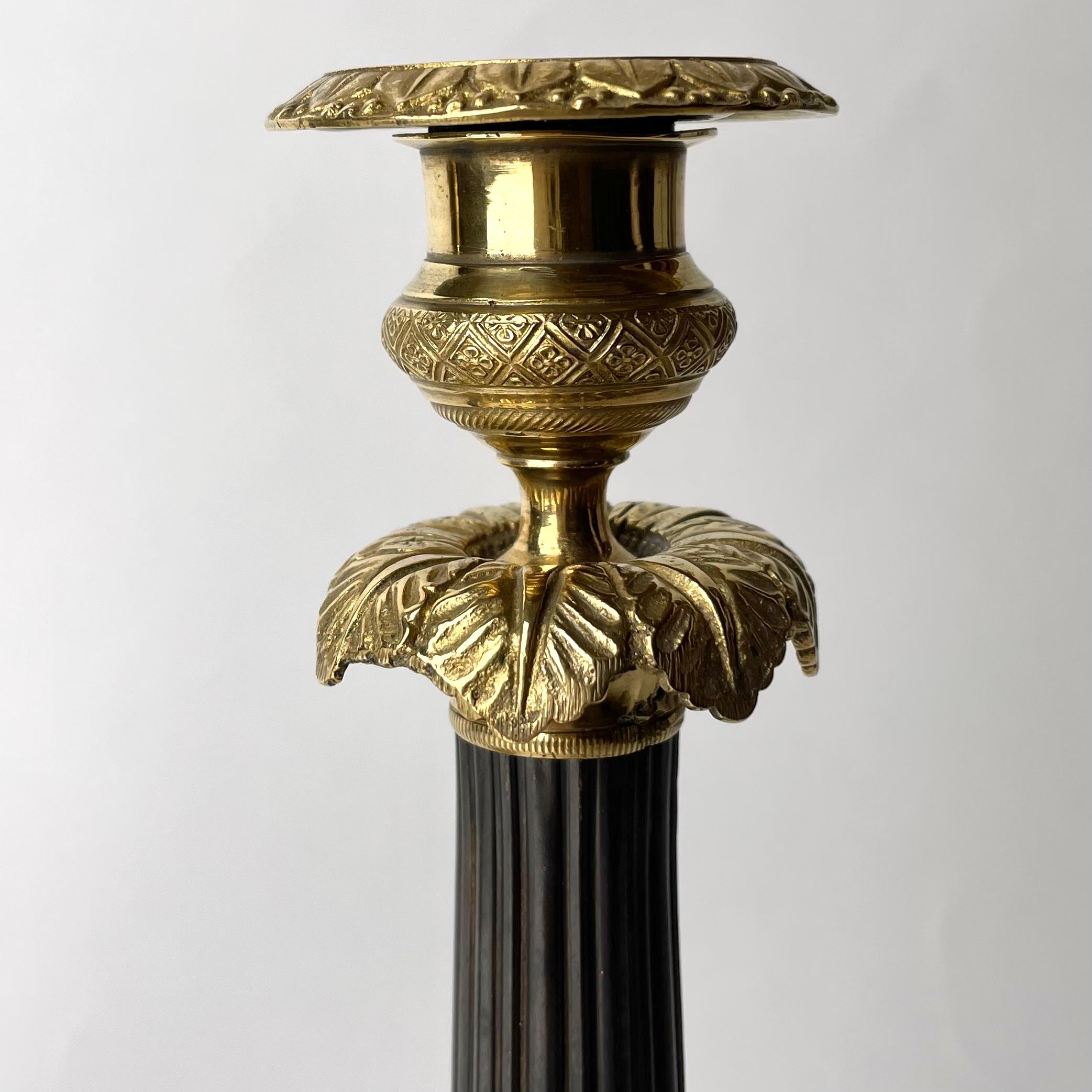 Bronze Pair of Empire Candlesticks in gilded and darkpatinated bronze from the 1820s For Sale