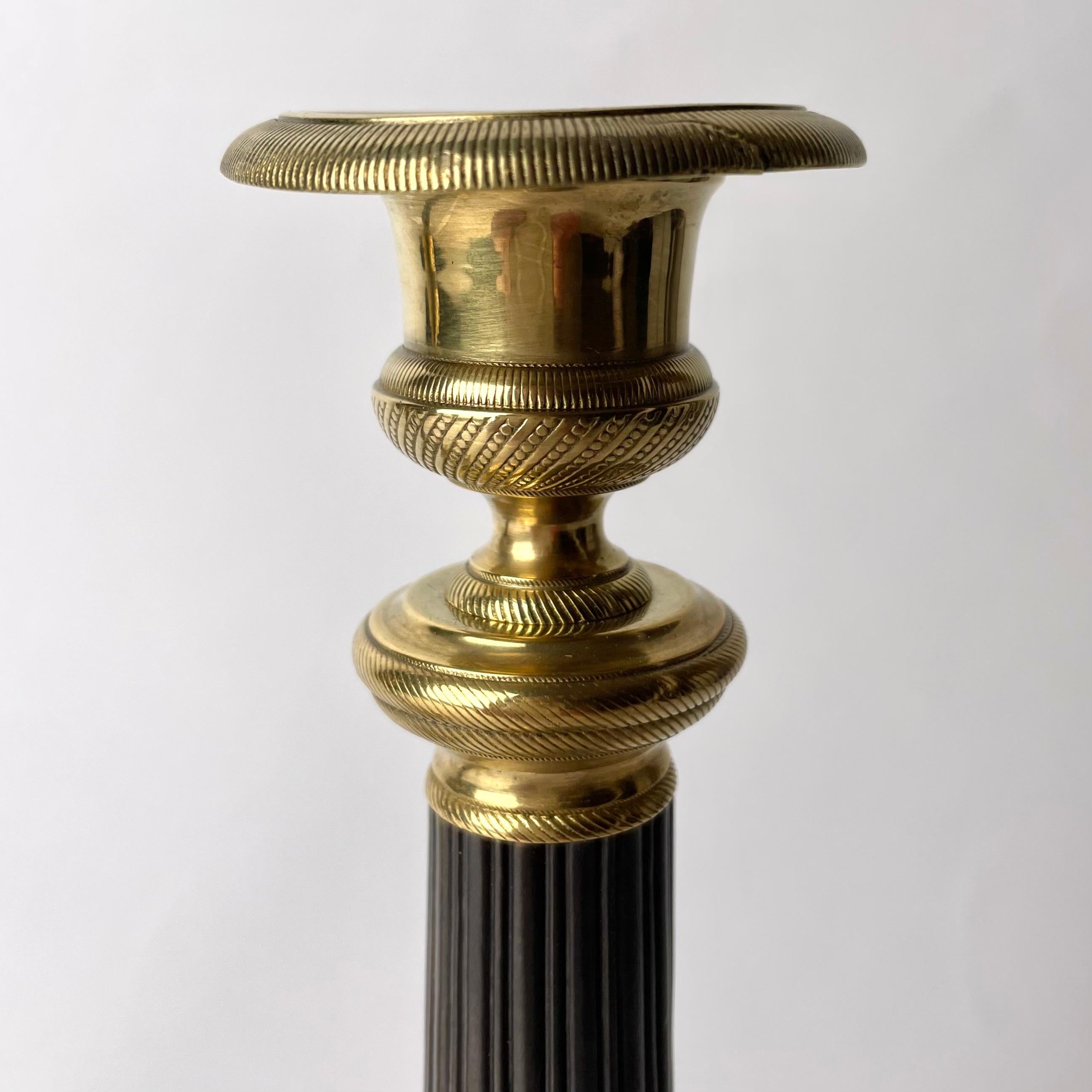 Bronze Pair of Empire Candlesticks in gilt and dark patinated bronze from the 1820s For Sale