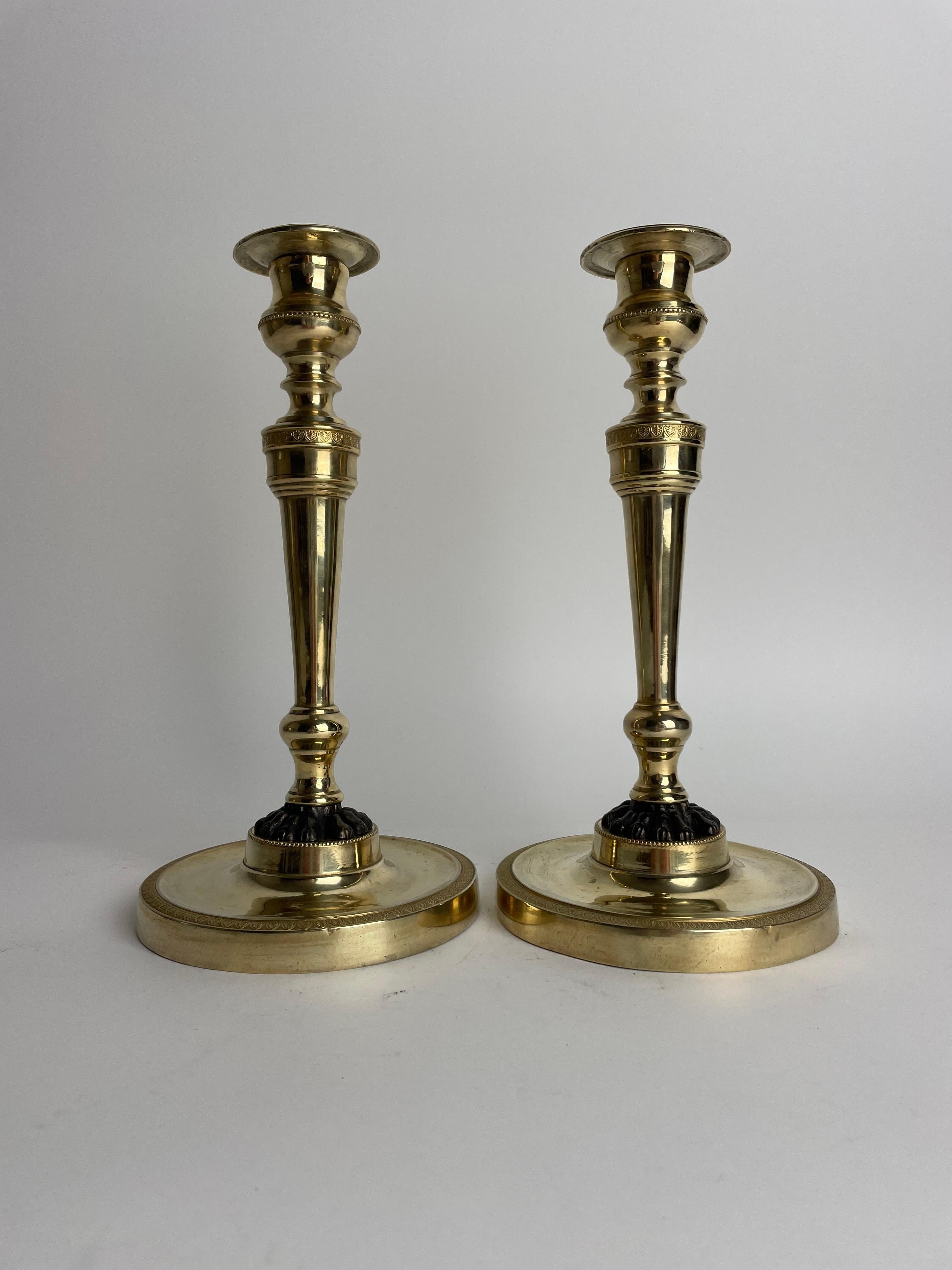 Stile impero Coppia di candelieri Impero in bronzo dorato con zampe di leone patinate scure. 1810s in vendita