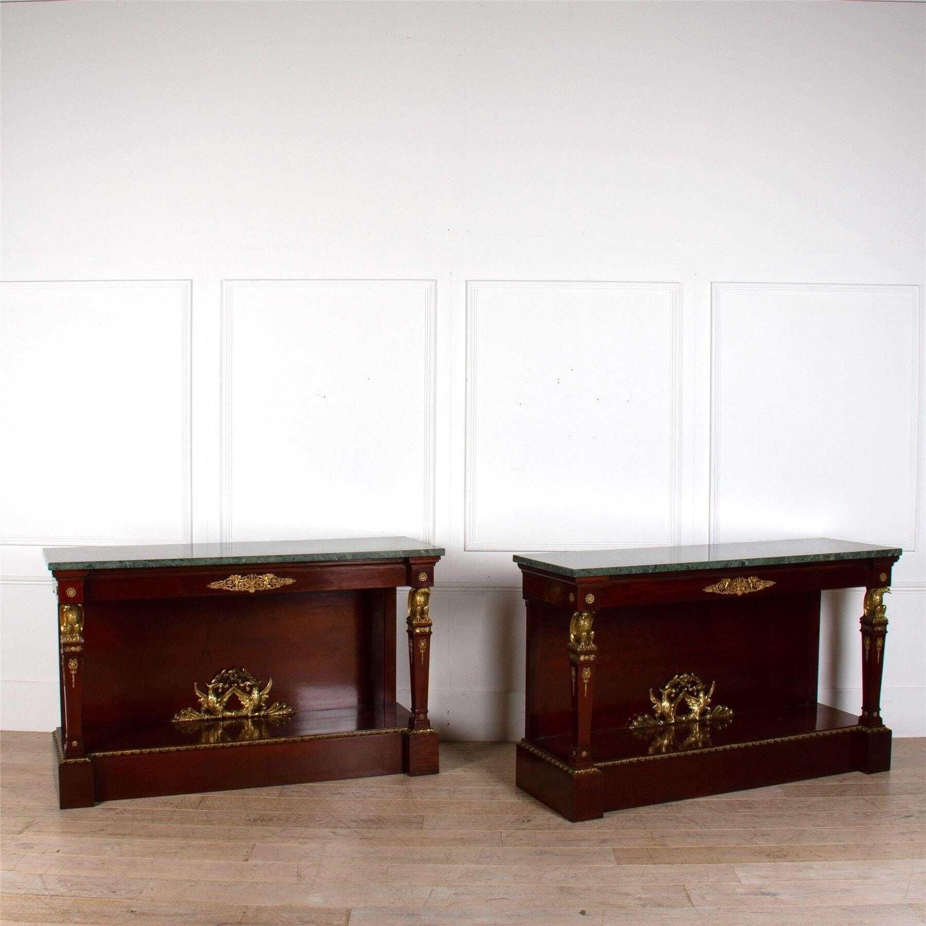 A large pair of Empire console tables with green marble tops and large scale ormolu mounts.
With symmetrical eagle motifs on the legs and in the bottom centre, the style and symbolism on these tables are typical of Empire furniture. 
These tables