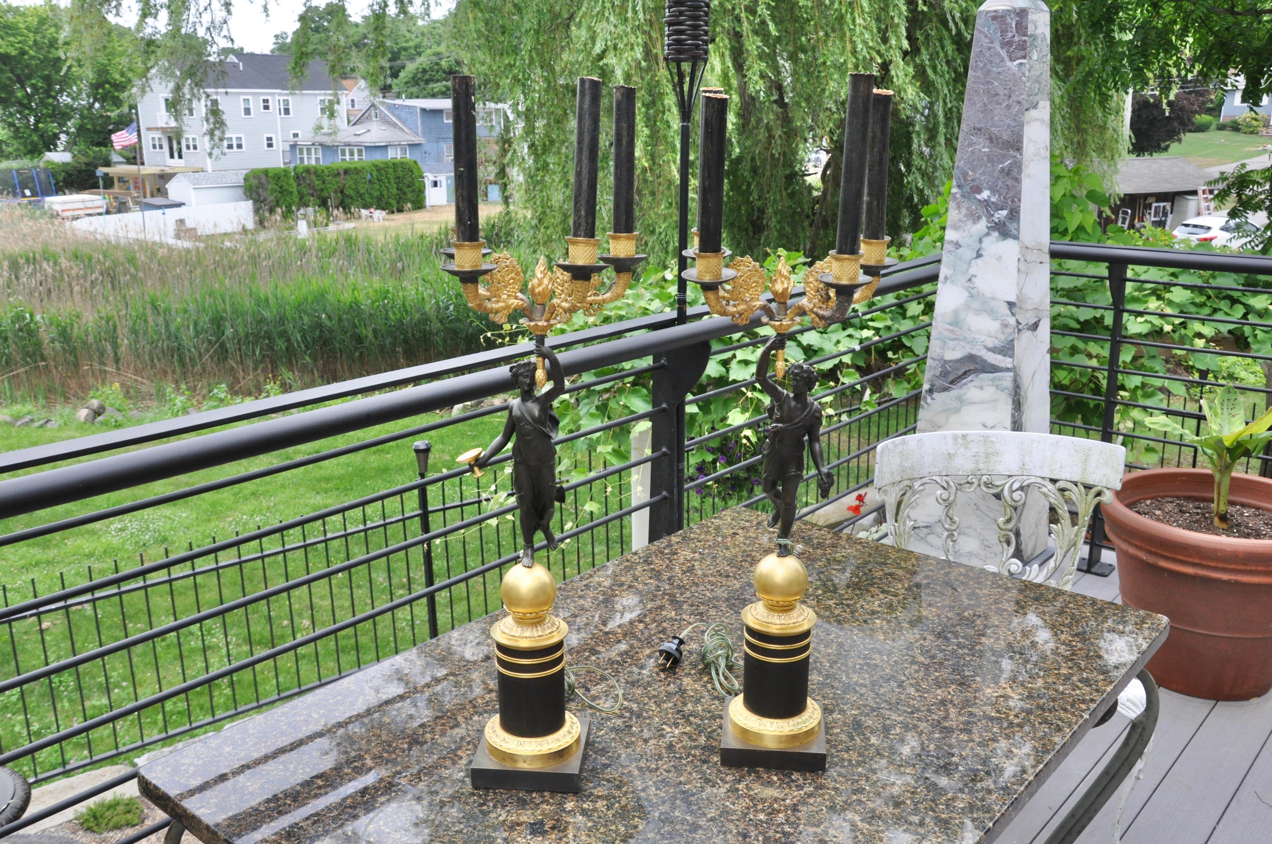 Paire de candélabres en bronze doré et patiné du 19e siècle, utilisés comme lampes. Baccantes figuratifs tenant des torchères. Période de l'Empire ou de Charles X. Bonne dorure au feu bruni et patine d'origine.