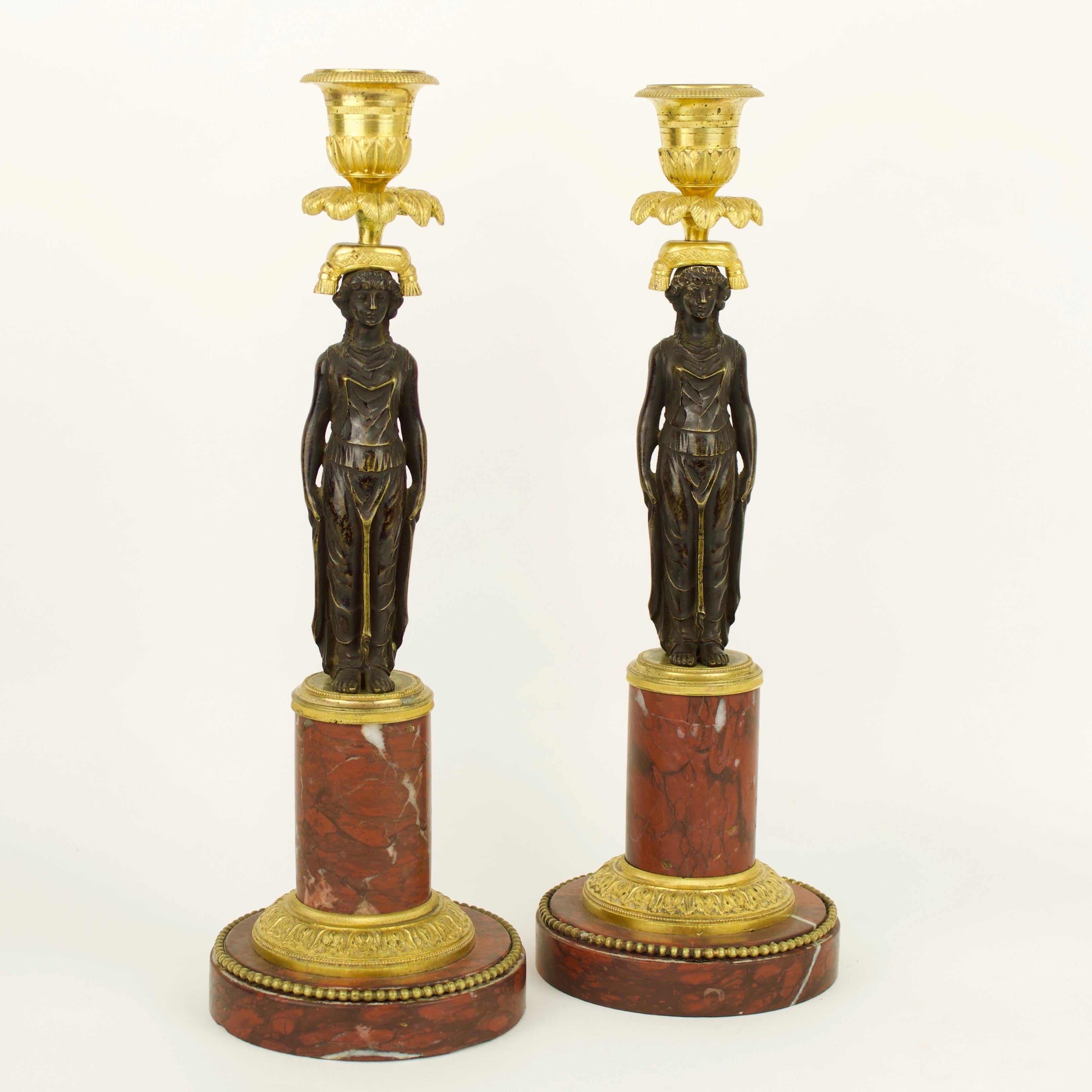 A beautiful French early 19th century Empire pair of ormolu and patinated bronze candlesticks with female figure decoration in the manner of Claude Galle: 

Each candlestick with a patinated bronze female caryatid wearing a classical tunic,
