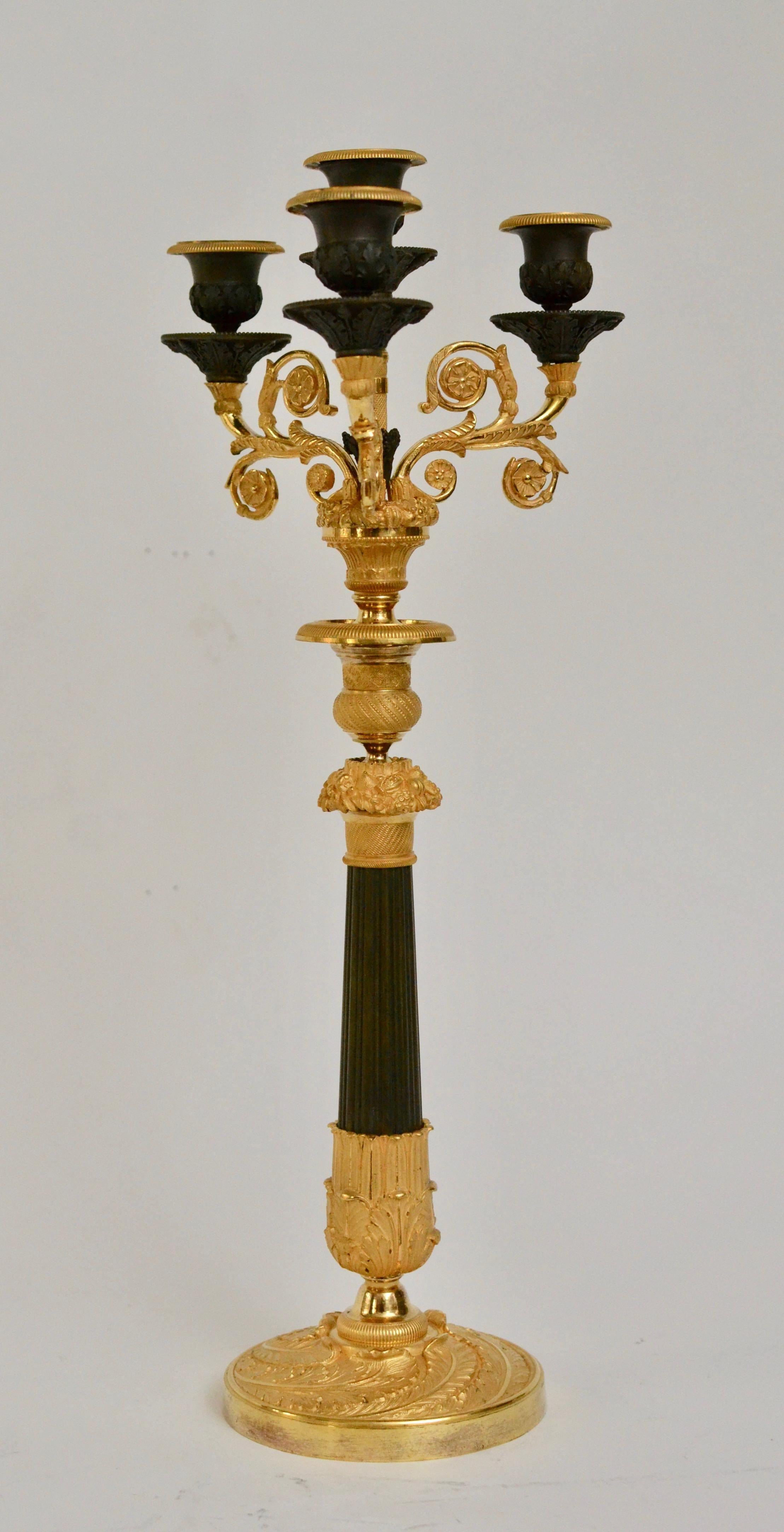 A pair of French Empire gilt and patinated bronze candelabra, circa 1825. Detachable top.