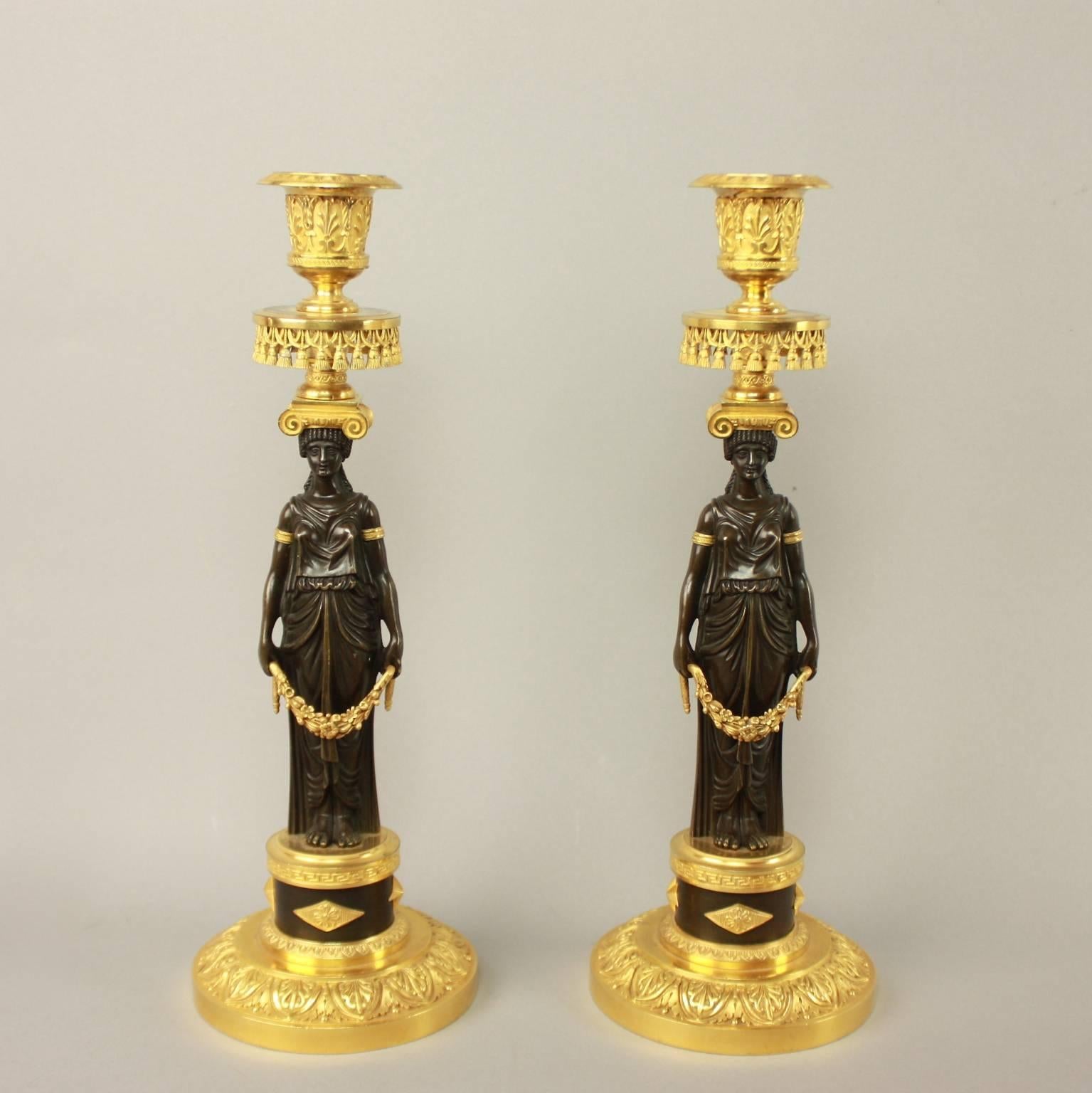 A fine pair of ormolu and patinated bronze candlesticks, each with a caryatid vestal virgin (ancient priestesses who protected the temple dedicated to the Roman goddess Vesta) or possible korai (female figures used as votive offerings to deities,