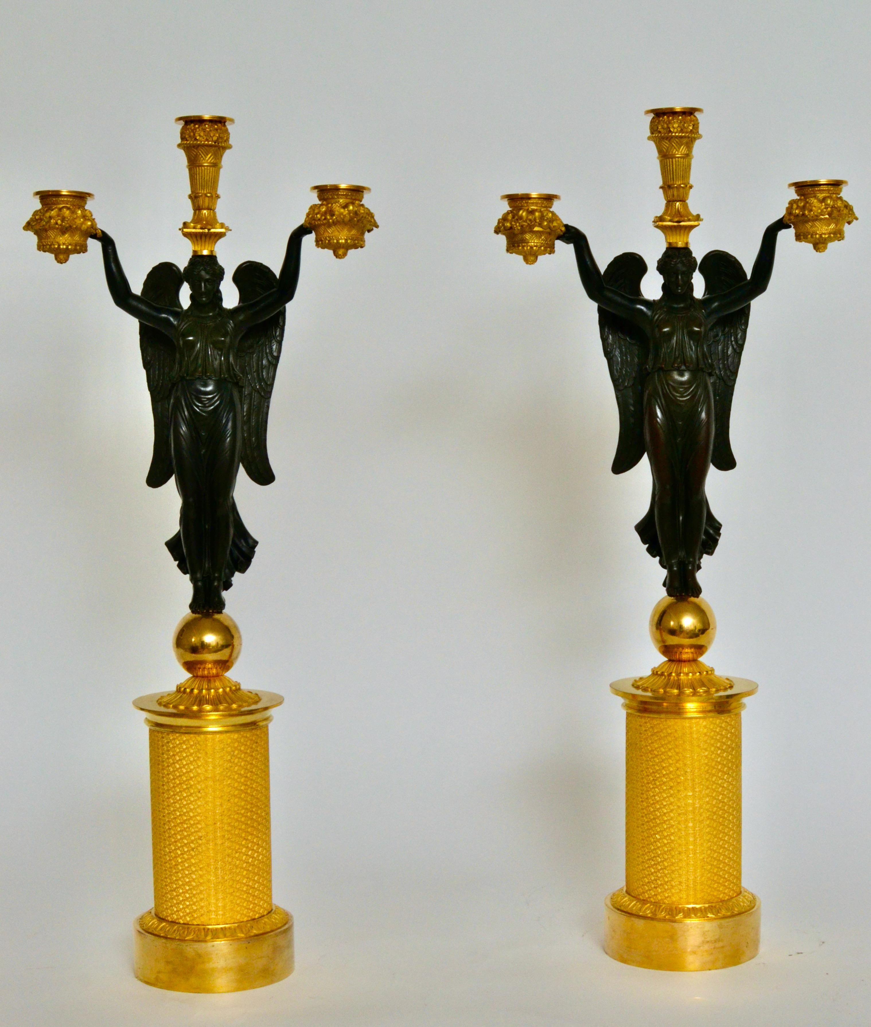 This rare pair of Empire period candelabra was designed by Pierre-Philippe Thomire and and most probably executed by Claude François Rabiat. There are known examples signed by Rabiat. They each have three lights, carried by winged Victories. These