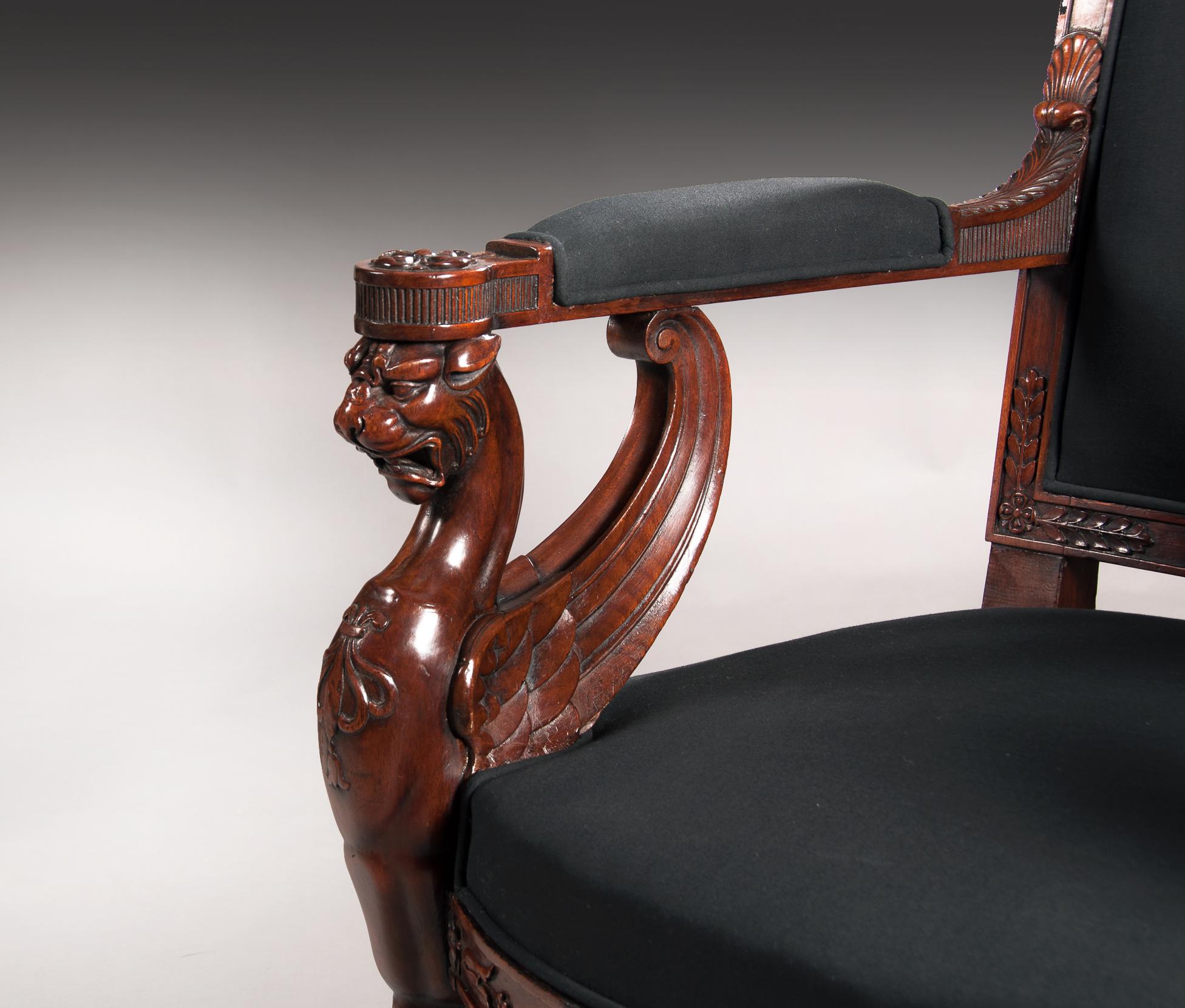 An extremely Fine and well executed pair of carved mahogany Empire period open fauteuils / armchairs, upholstered in a black calico, by repute from a Royal collection.

European, circa 1810.

The gently raked, out-scrolled rectangular backs,