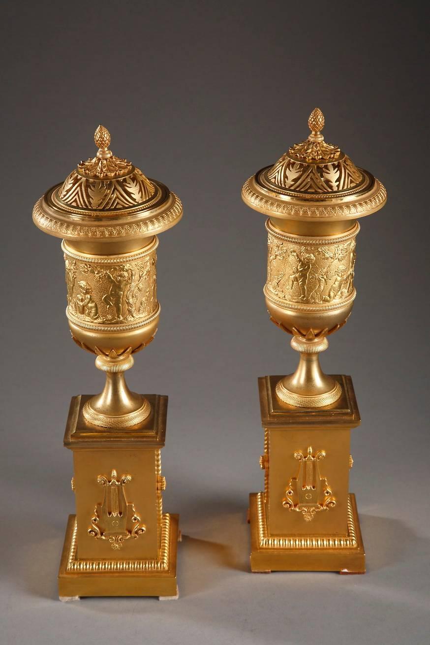 Exceptional pair of potpourri and candlestick vases with their openwork lids decorated with foliage and a pine cone filial. Candle sockets lie under the lids, and are sculpted with grooves. The body of each vase is adorned with a frieze framed with