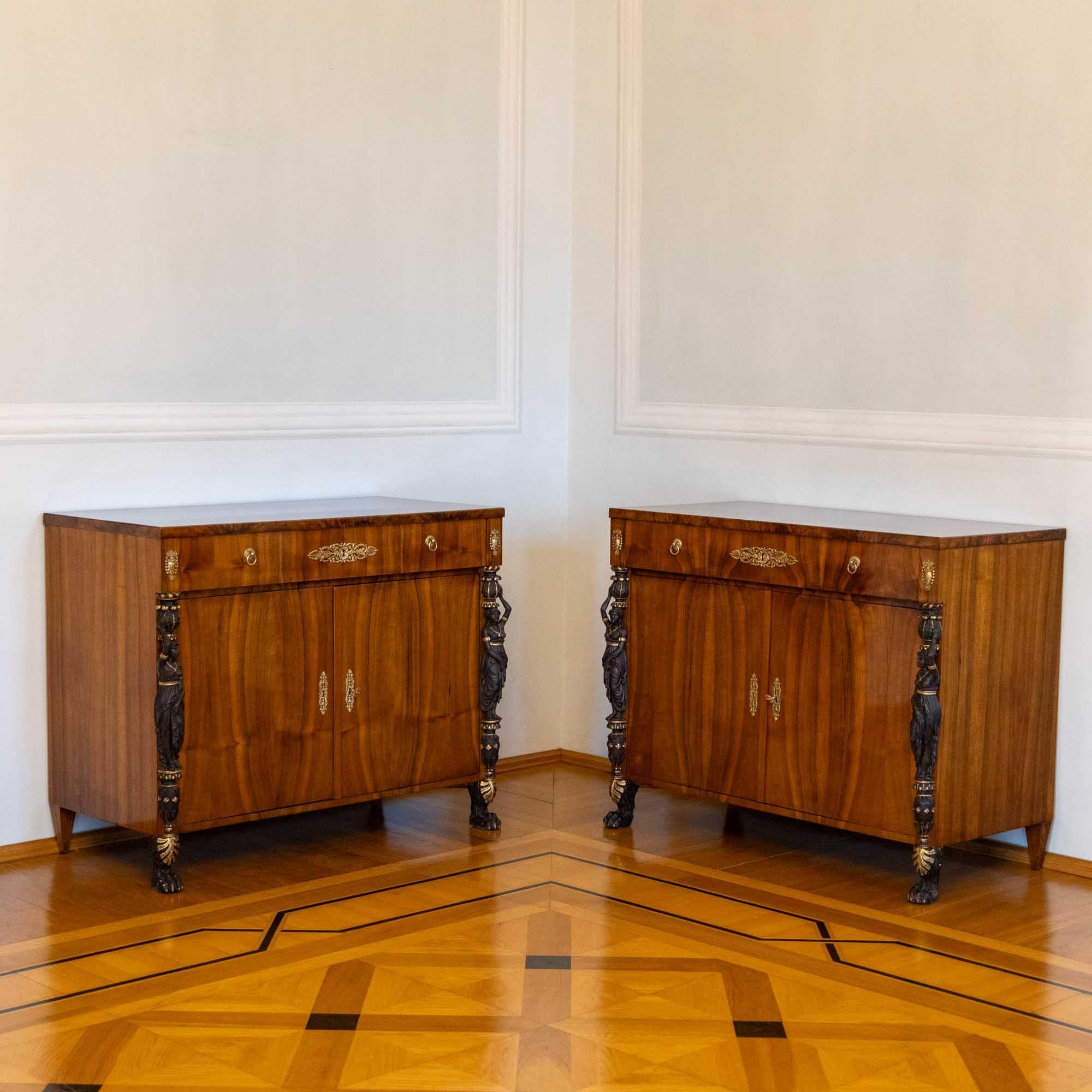 Pair of trumeau sideboards with flanking carved caryatids in the Retour d'Egypte style. The sideboards are fitted with two doors and a wide drawer. The carved figures are blackened and the details are heightened in gold. The rich fittings in