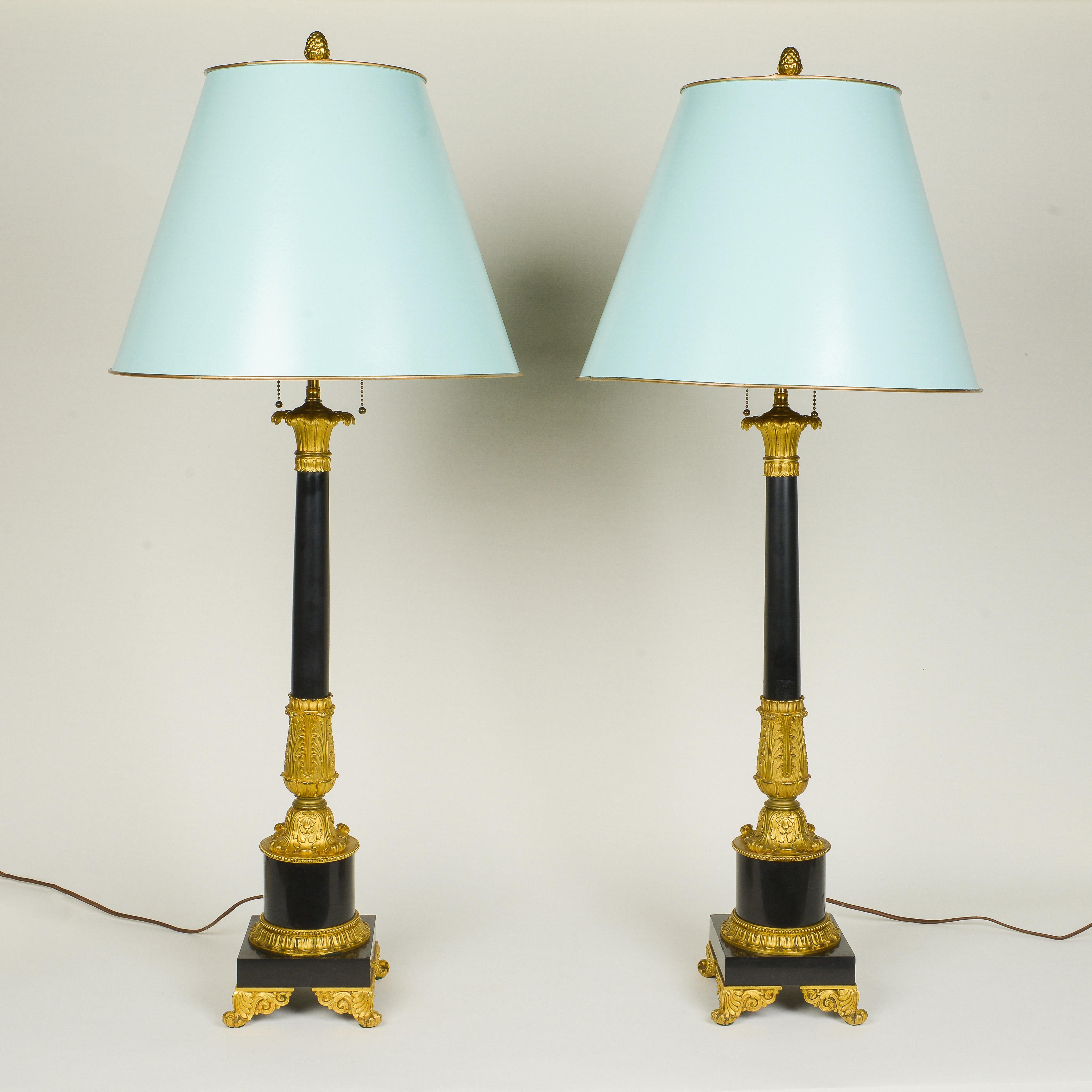 Each candleholder of columnar form surmounted with ormolu stiff-leaf capitals and with acanthus-wrapped base, on pedestal bases with outswept scrolling feet. Fitted with two brass bulb sockets. Adjustable. Later mounded as a lamps. With duck blue
