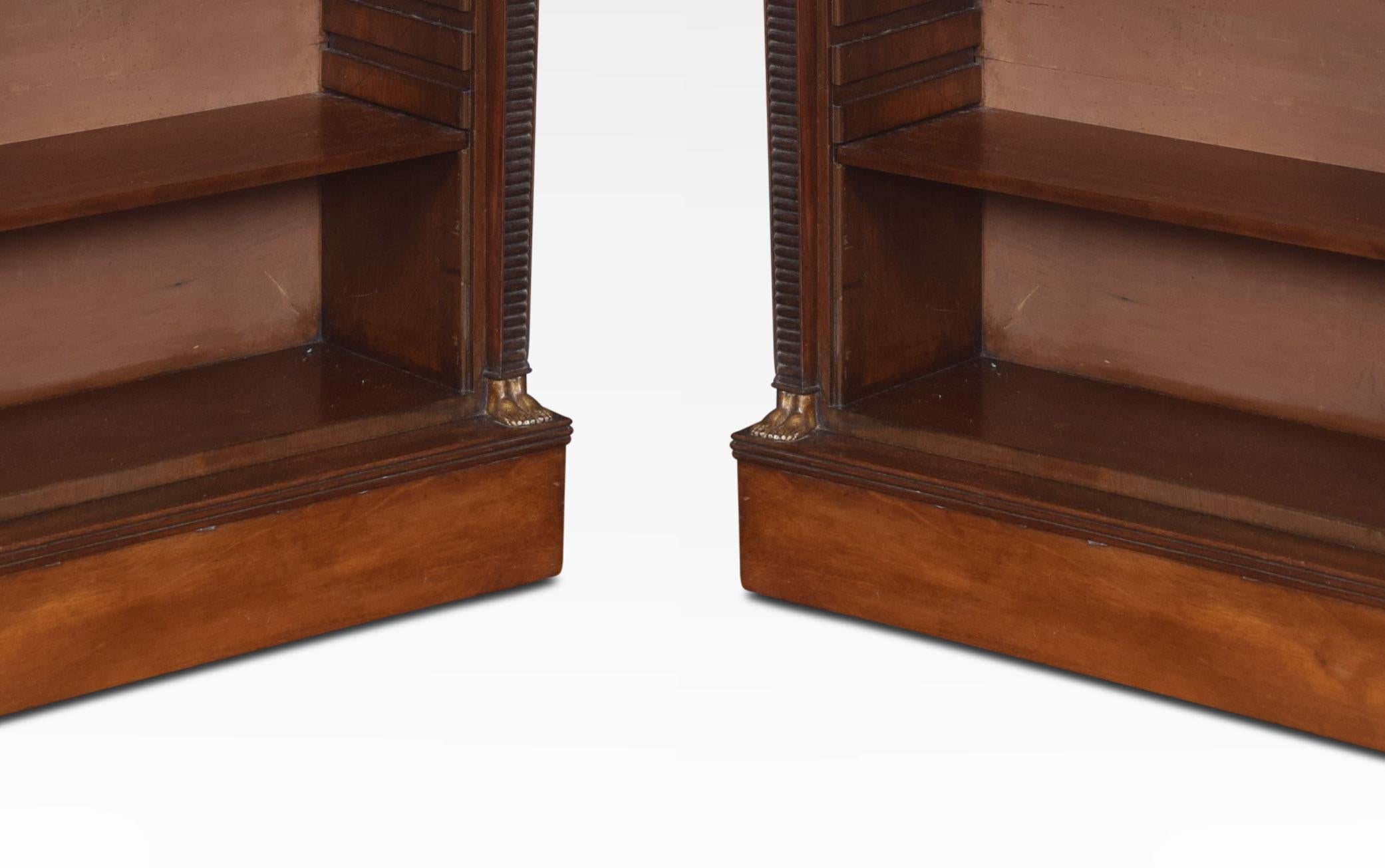 A pair of regency style mahogany open bookcases. The rectangular tops above gilded mounted freezes to the open shelves fitted with two adjustable shelves in each section, flanked by Egyptian influence columns. All raised up on plinth