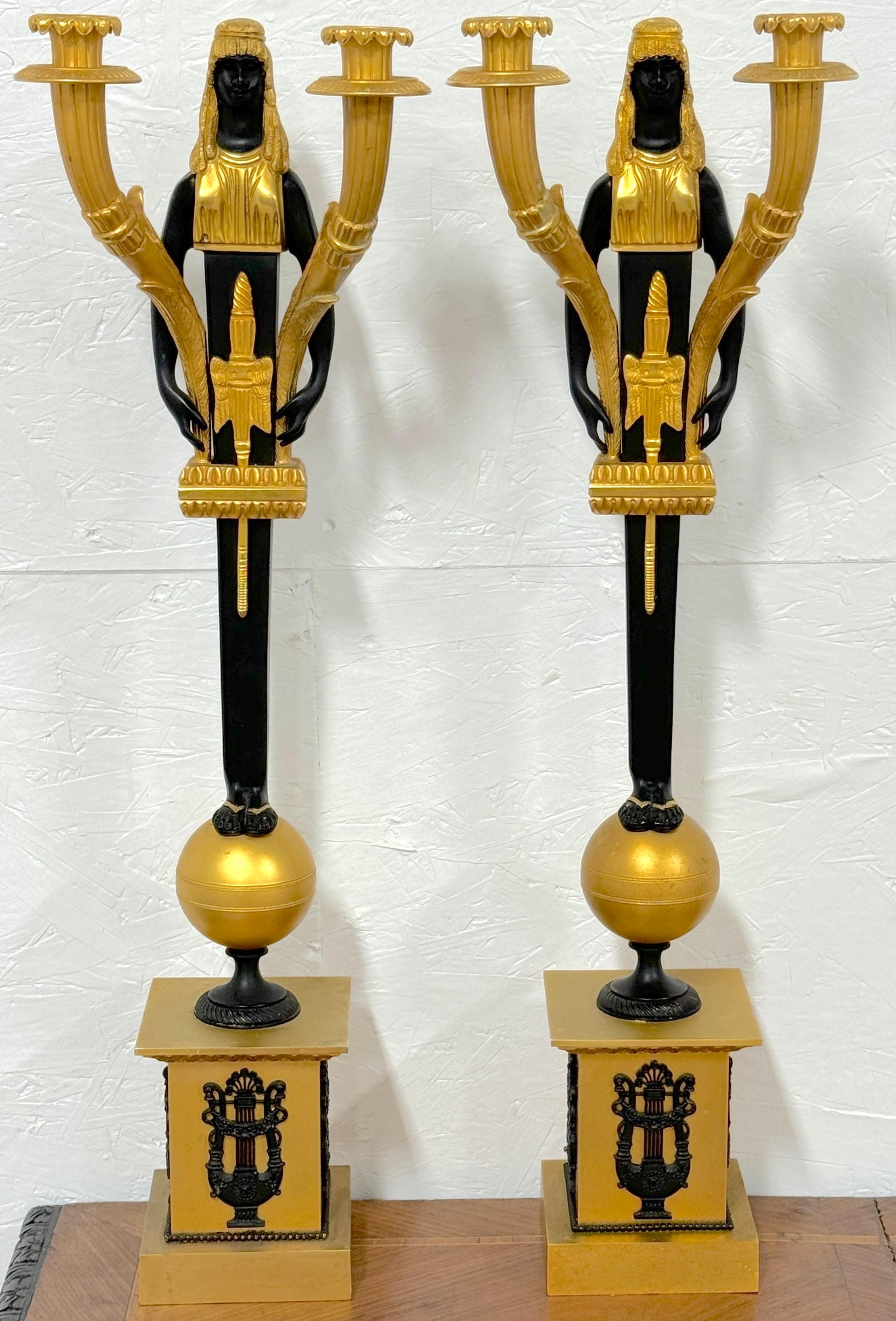 Coppia di candelabri a due luci in stile impero con cariatide egiziana in ormolu e patina, Francia, XX secolo 

Una coppia di squisiti candelabri a due luci in stile Impero, realizzati in Francia nel XX secolo. Questi splendidi pezzi sono alti 26,5