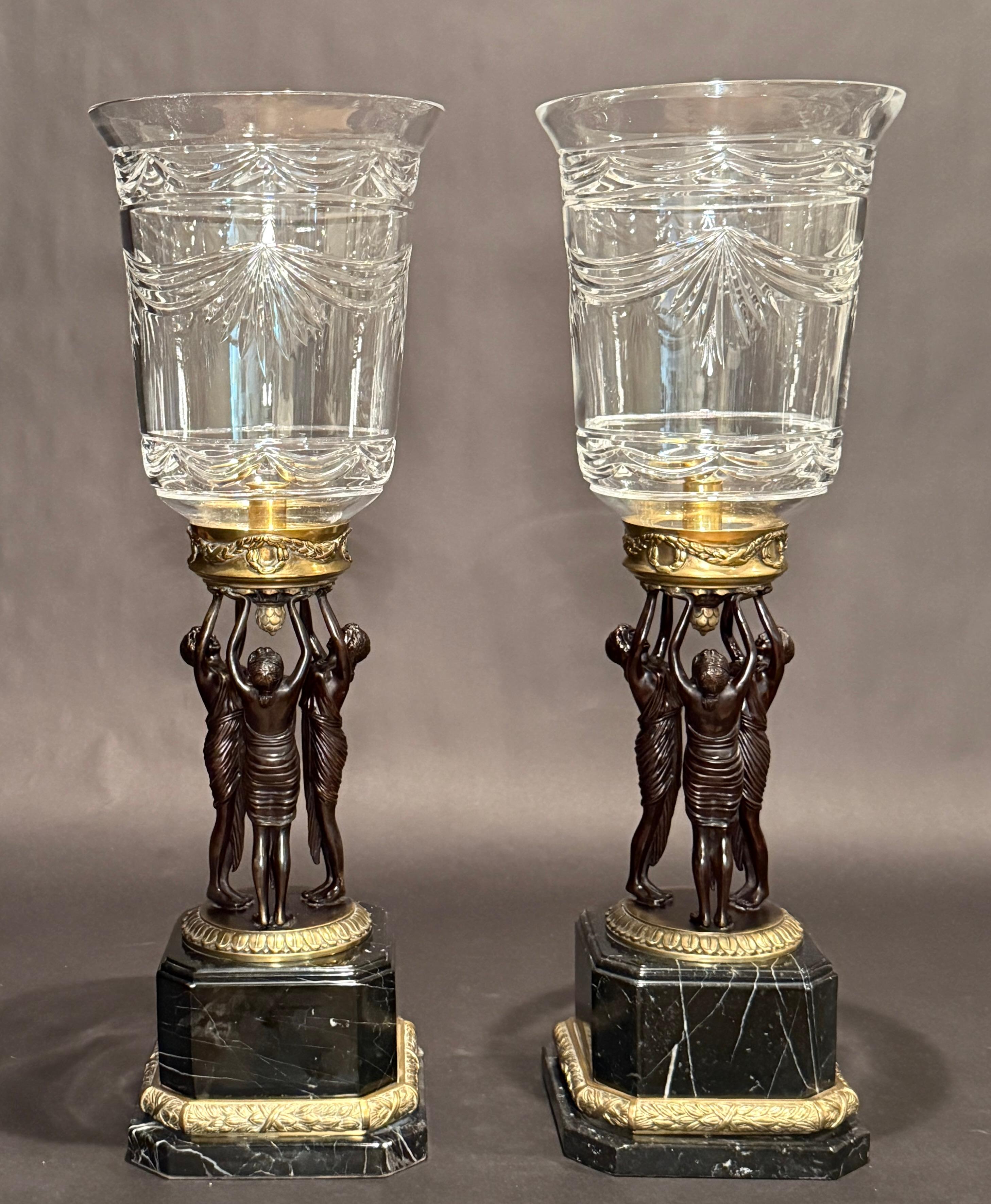 Fine and large patinated bronze and marble candle lamps with fabulous wheel cut hurricane shades. Three women, 