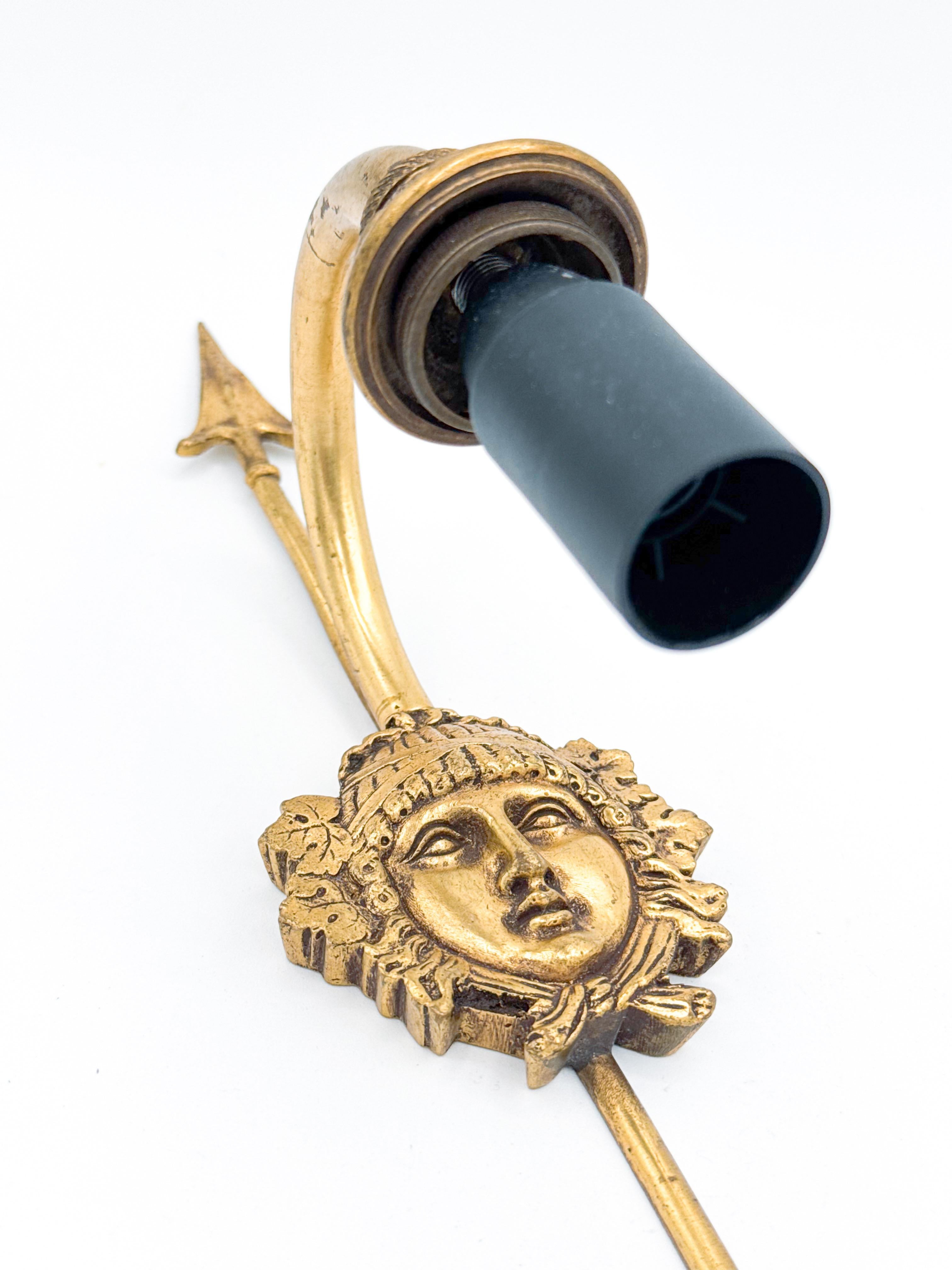 Cette paire exquise d'appliques murales en bronze doré de style Empire allie sans effort la grandeur classique à de subtiles influences Art déco, ce qui en fait un ajout rare et élégant à tout intérieur. Chaque applique présente une plaque arrière