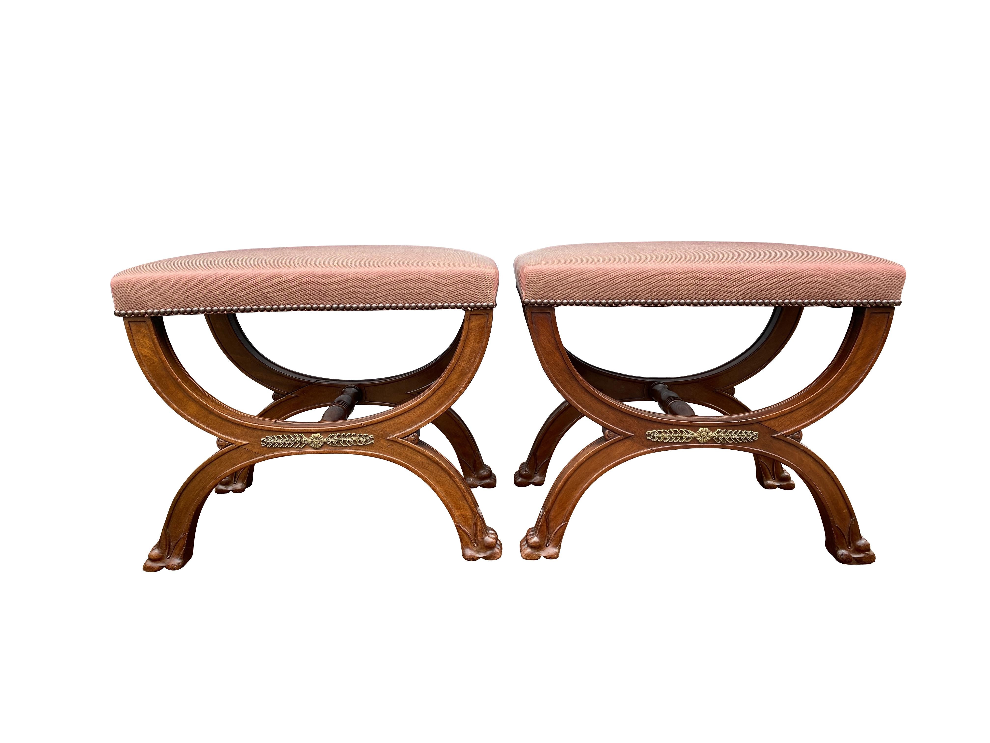 Rectangular upholstered seats with klismos form bases with turned stretchers, bronze mounts and paw feet.